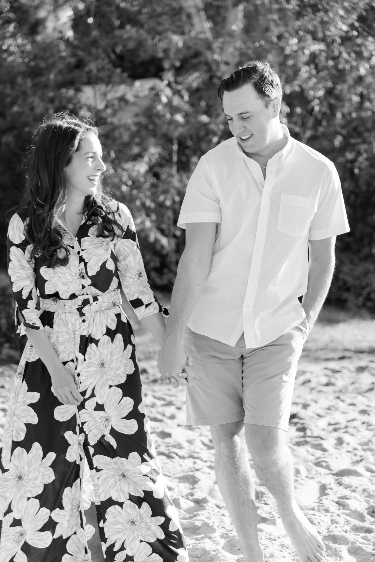 Black and white photo of a couple laughing together on a sandy beach.