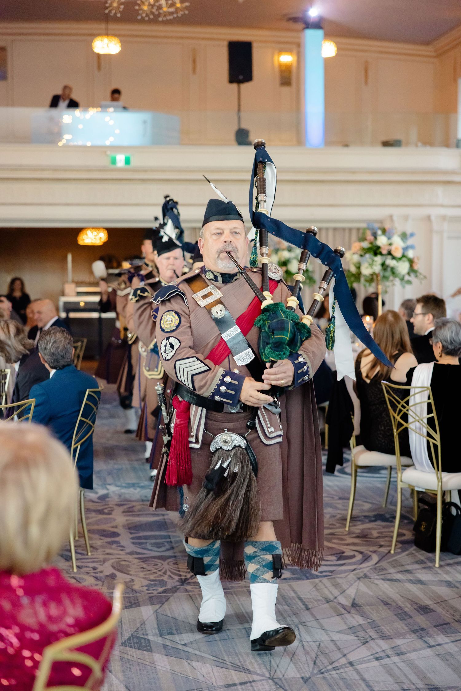 A bagpiper in traditional Scottish attire performs at an elegant wedding reception.