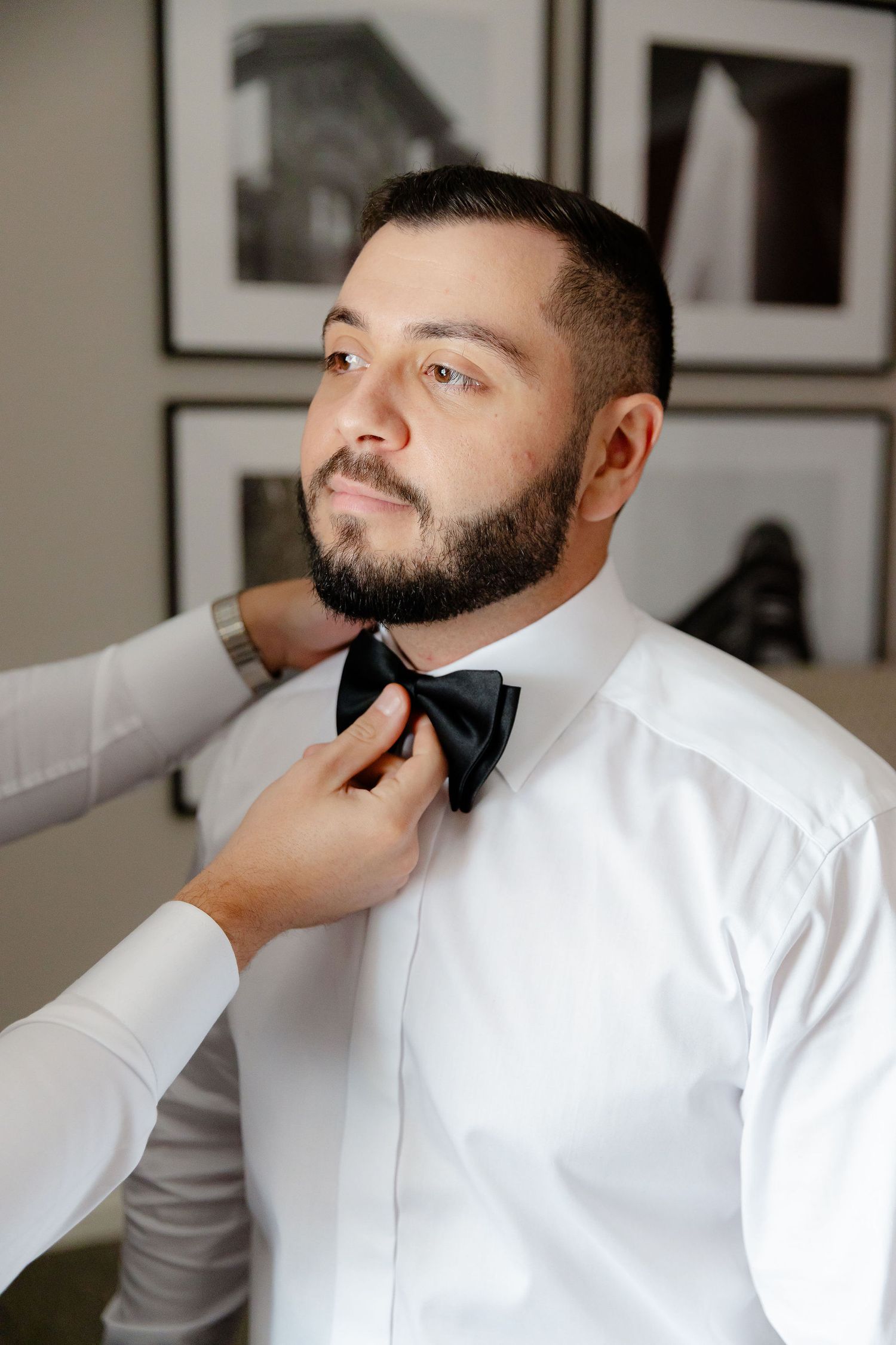 A man in a crisp white dress shirt gets his dark beard professionally groomed and styled in a series of photos.