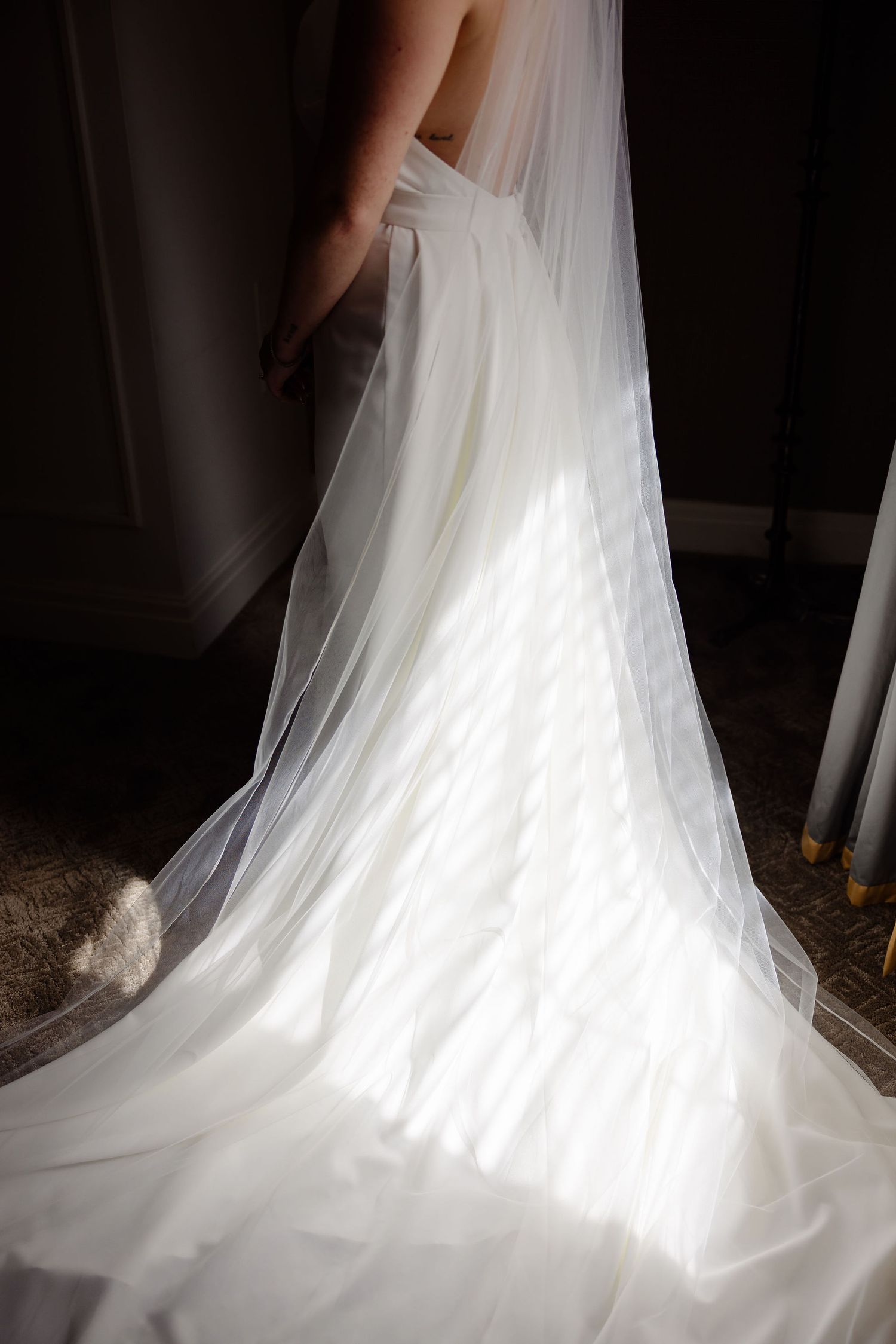 Dramatic lighting highlights the flowing train of a white wedding gown in multiple angles.