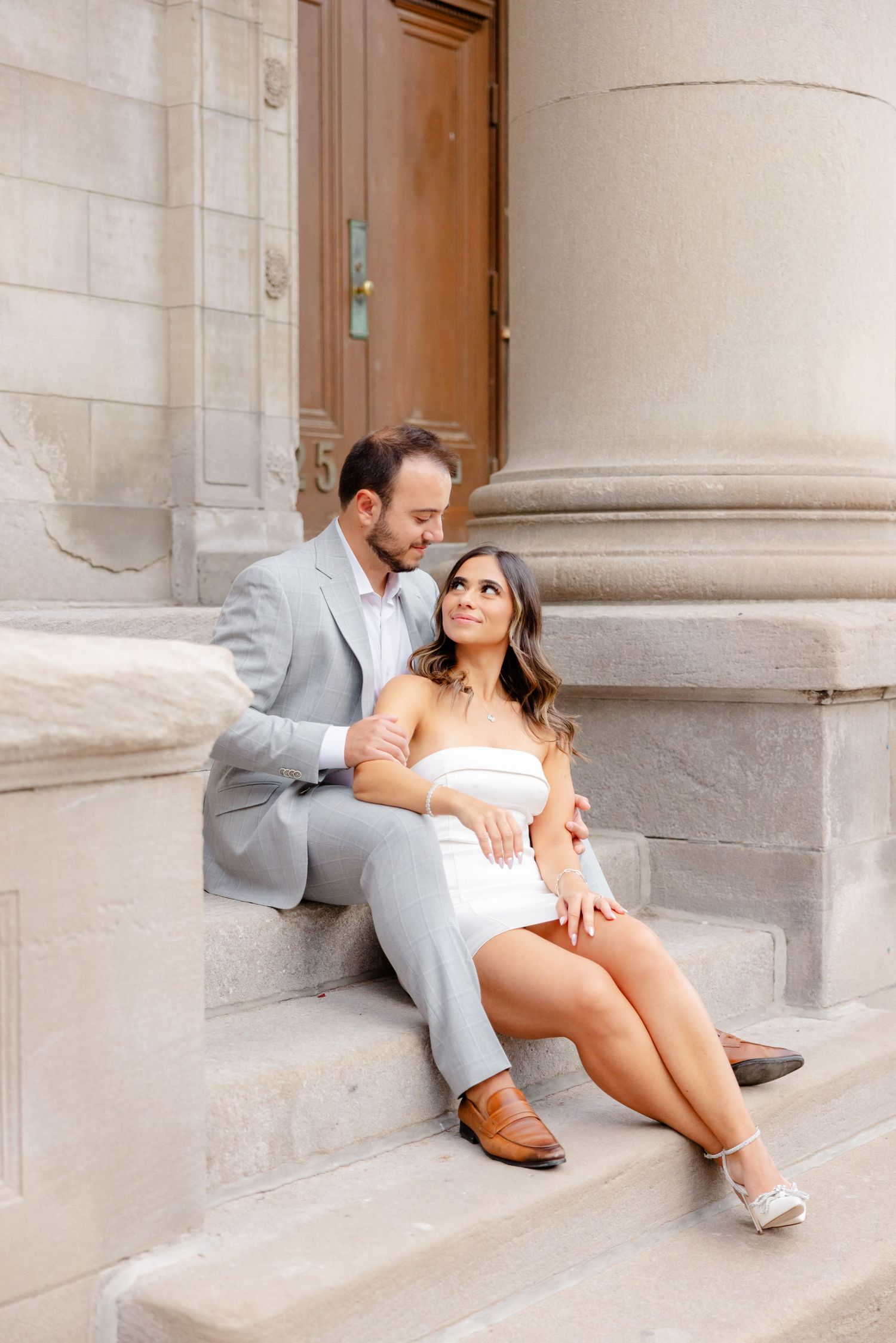 Romantic moment captured on grand stone steps with historic building details.