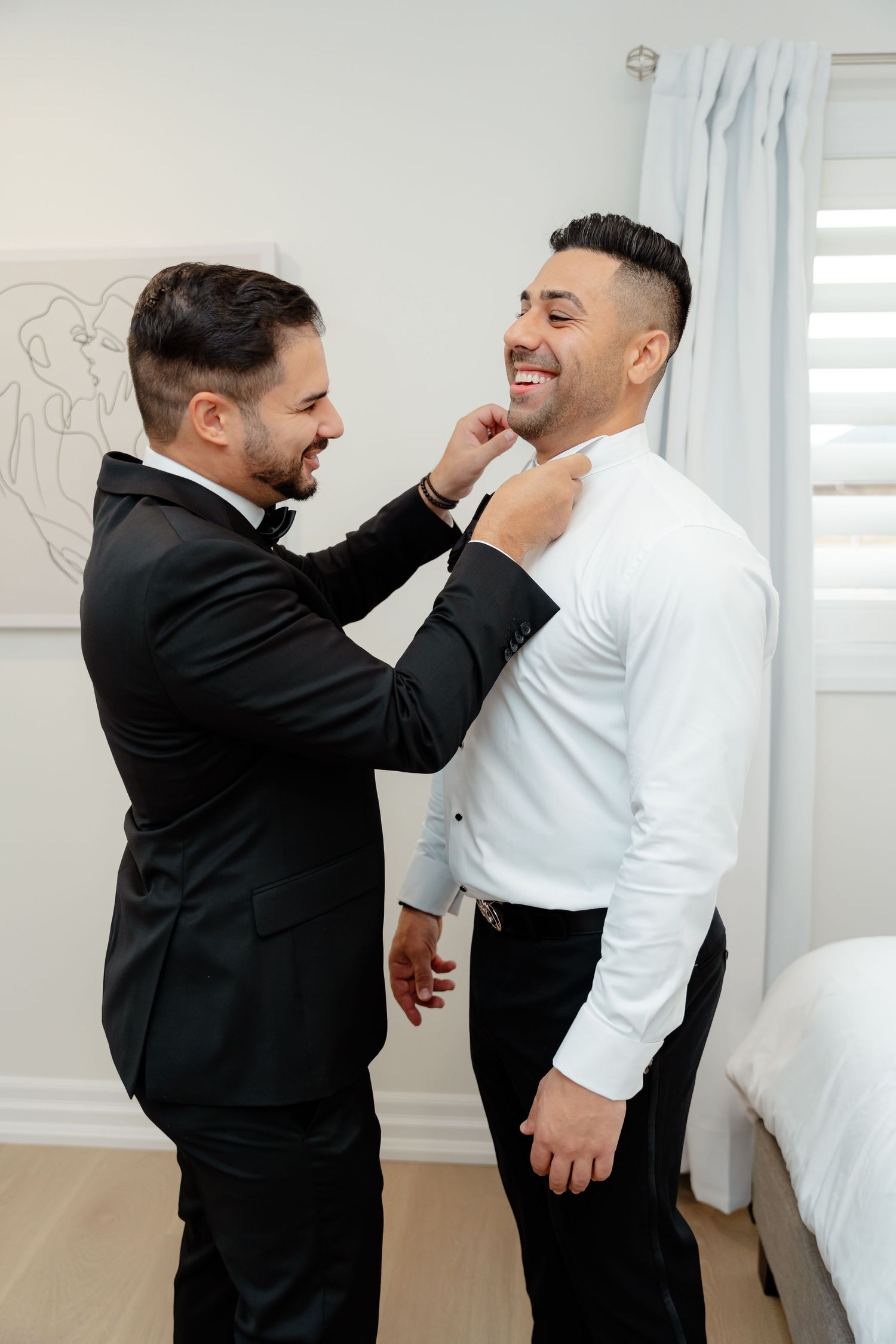 Two people helping with formal attire adjustments during preparation.