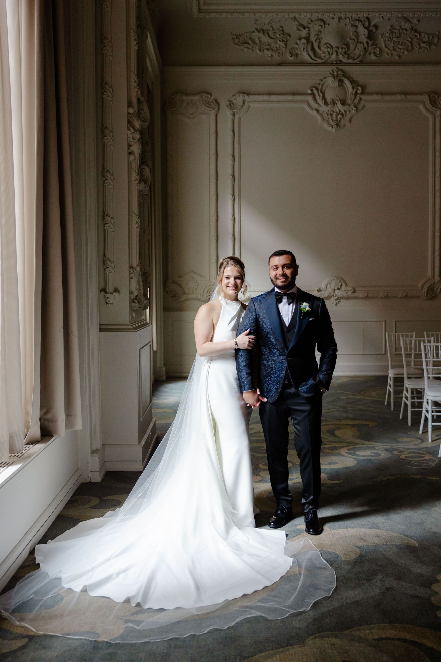 Wedding couple shares candid moments in an elegant room with classic architectural details.