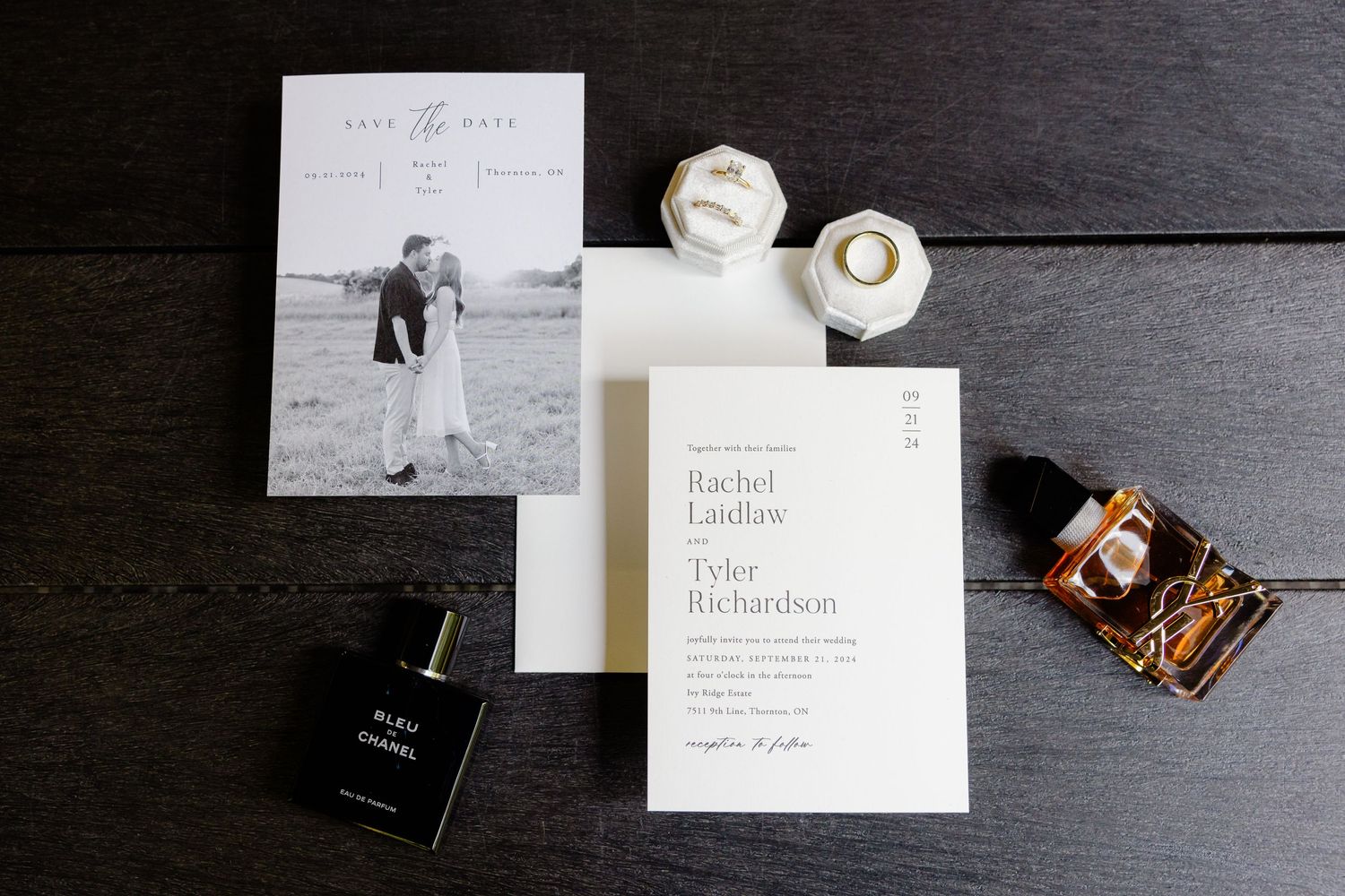 Wedding details including invitations, perfume bottle, and decorative items arranged on dark surface.