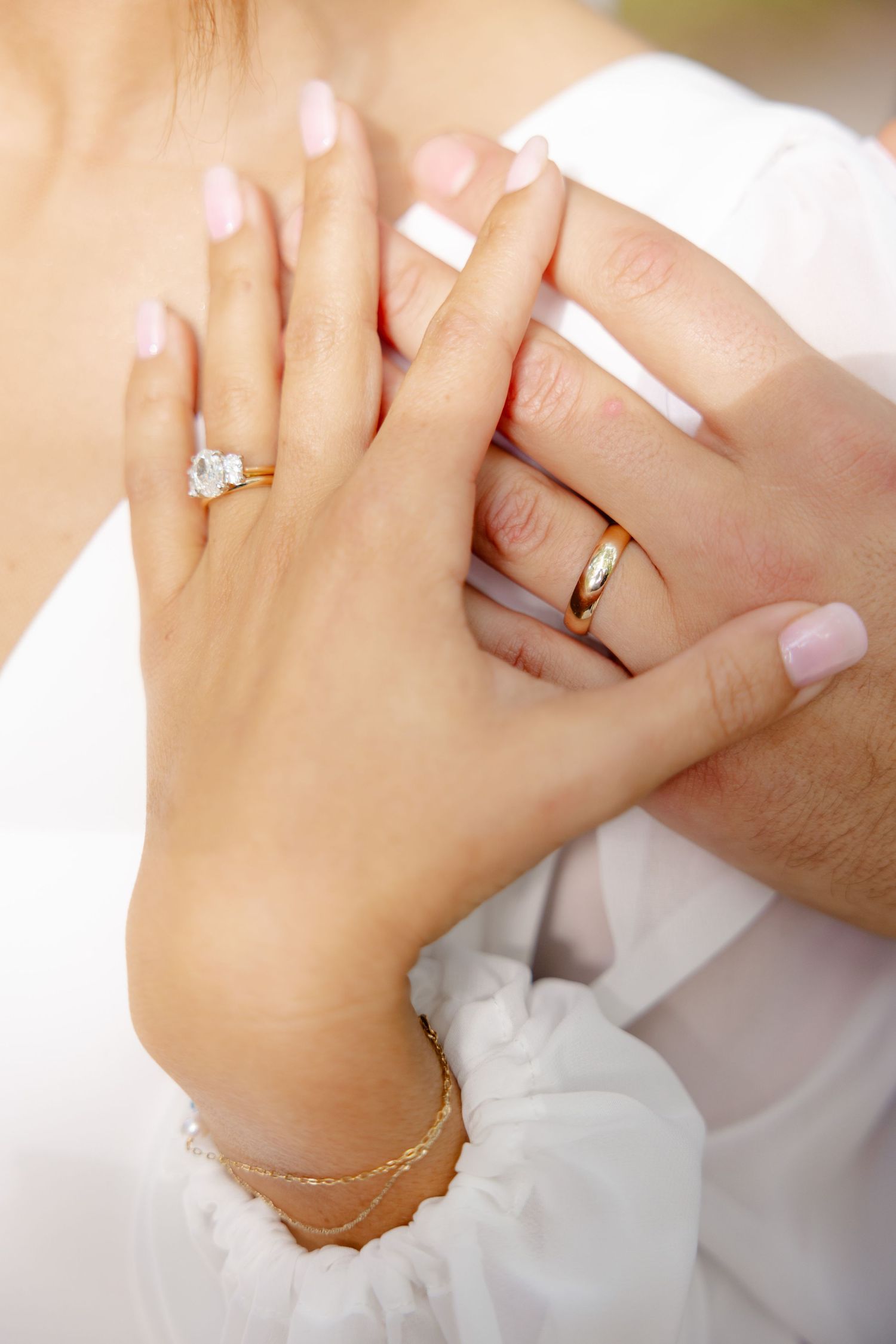 Wedding rings and engagement ring detail shot with bride's manicured hands.
