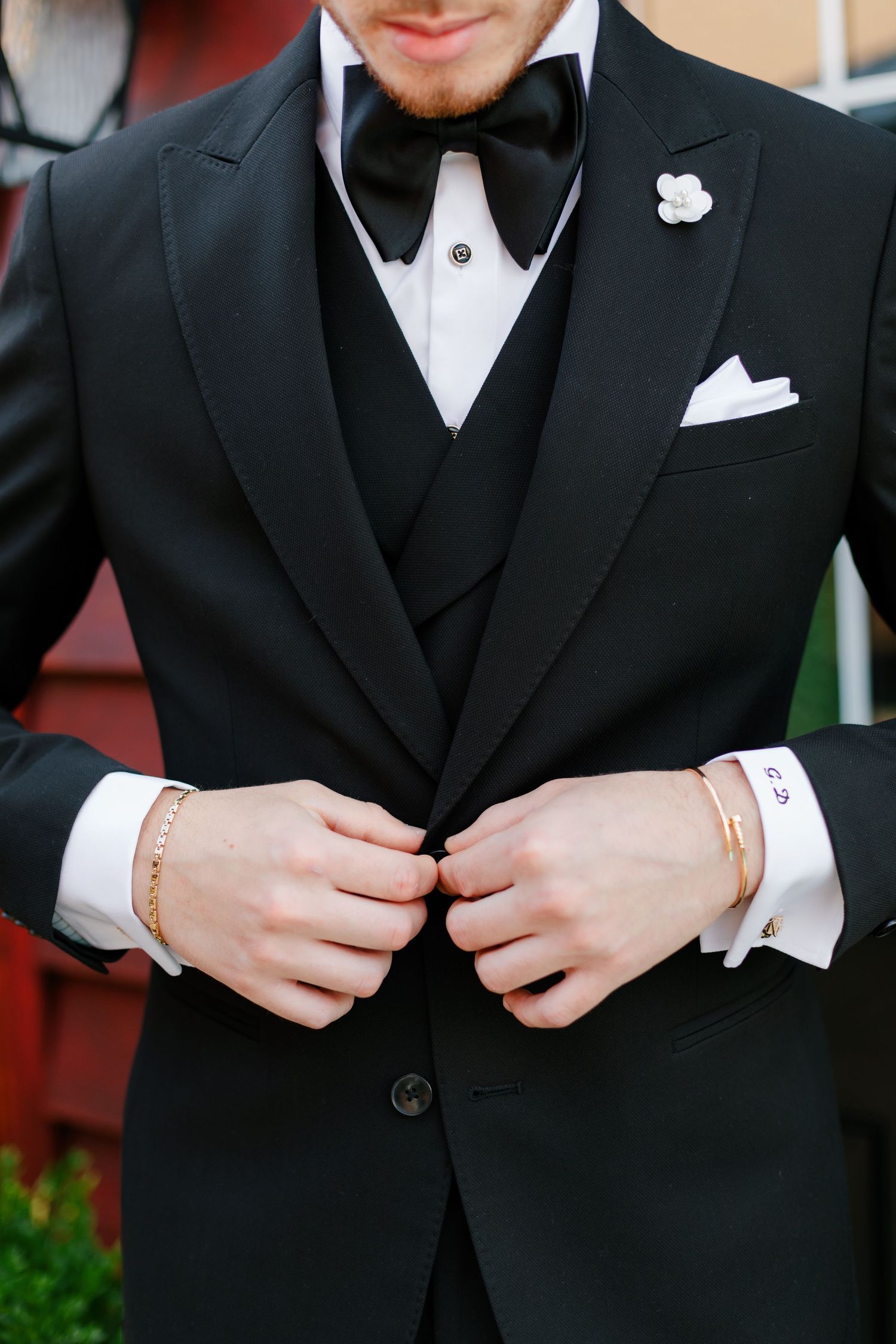 Close-up detail of a black tuxedo with bow tie, white pocket square and boutonniere.