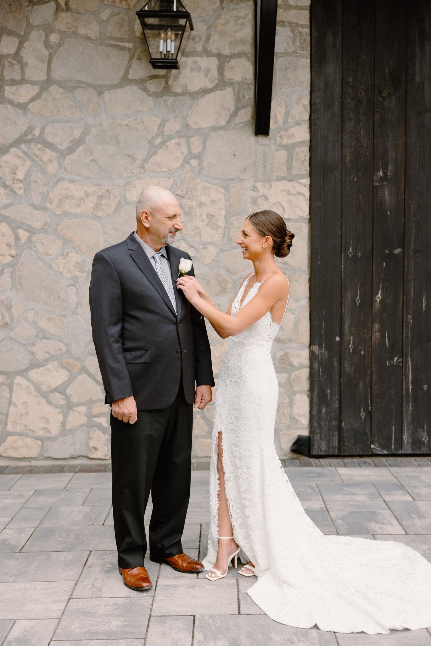 Sweet moment captured between two people in formal attire against a stone wall backdrop.