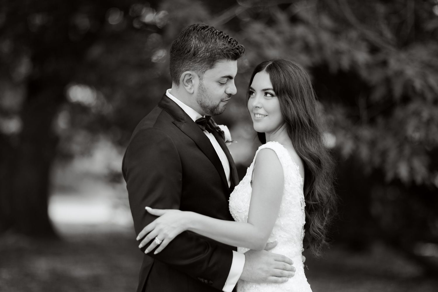 Black and white romantic portrait of newlyweds embracing outdoors.