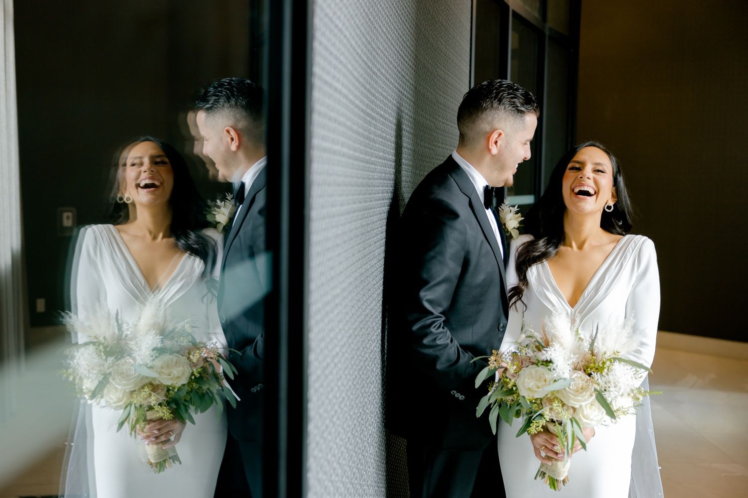 Candid wedding photography captures genuine laughter and joy between newlyweds near reflective surfaces.