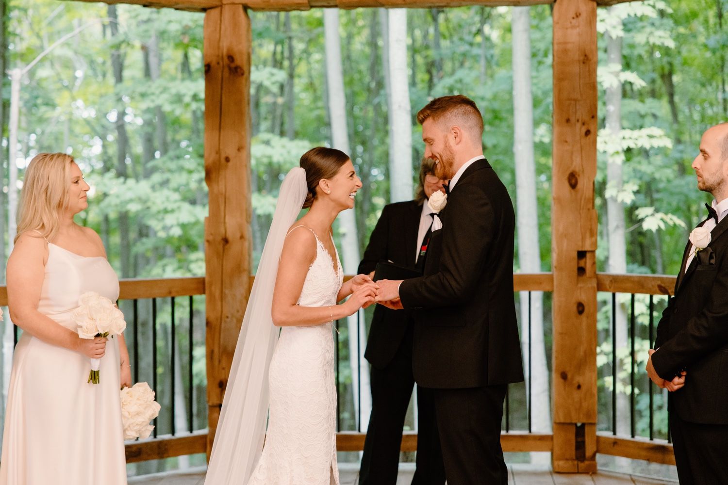 Intimate wedding ceremony unfolds in a wooden pavilion with forest views.