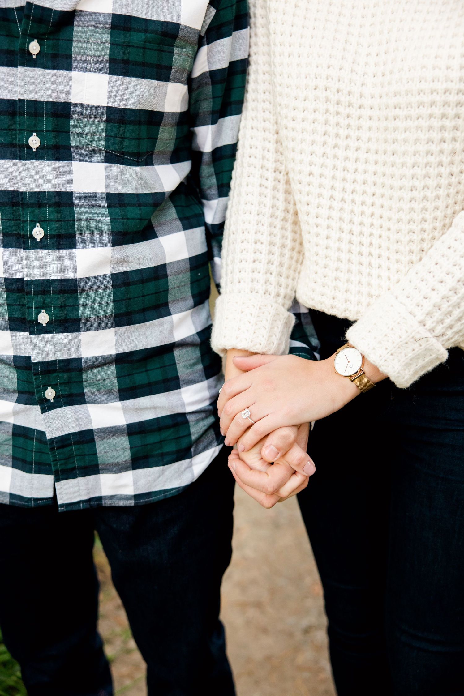 Close-up of hands holding while wearing green plaid flannel and white knit sweater.