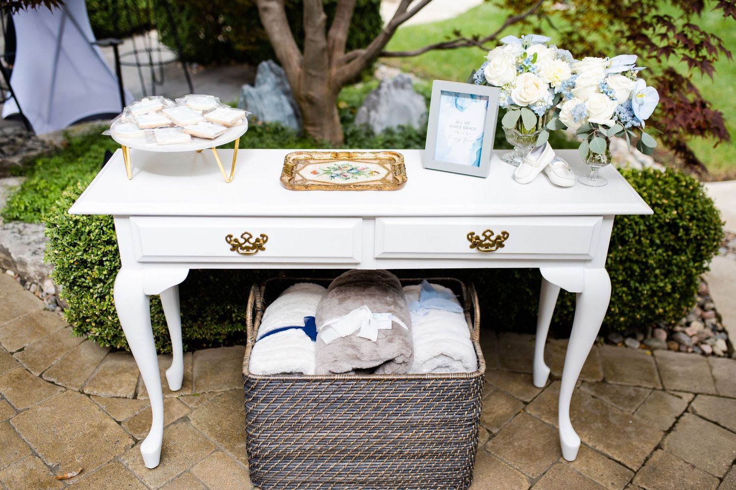 Elegant white vintage console table decorated with floral arrangements and accessories for a special event.