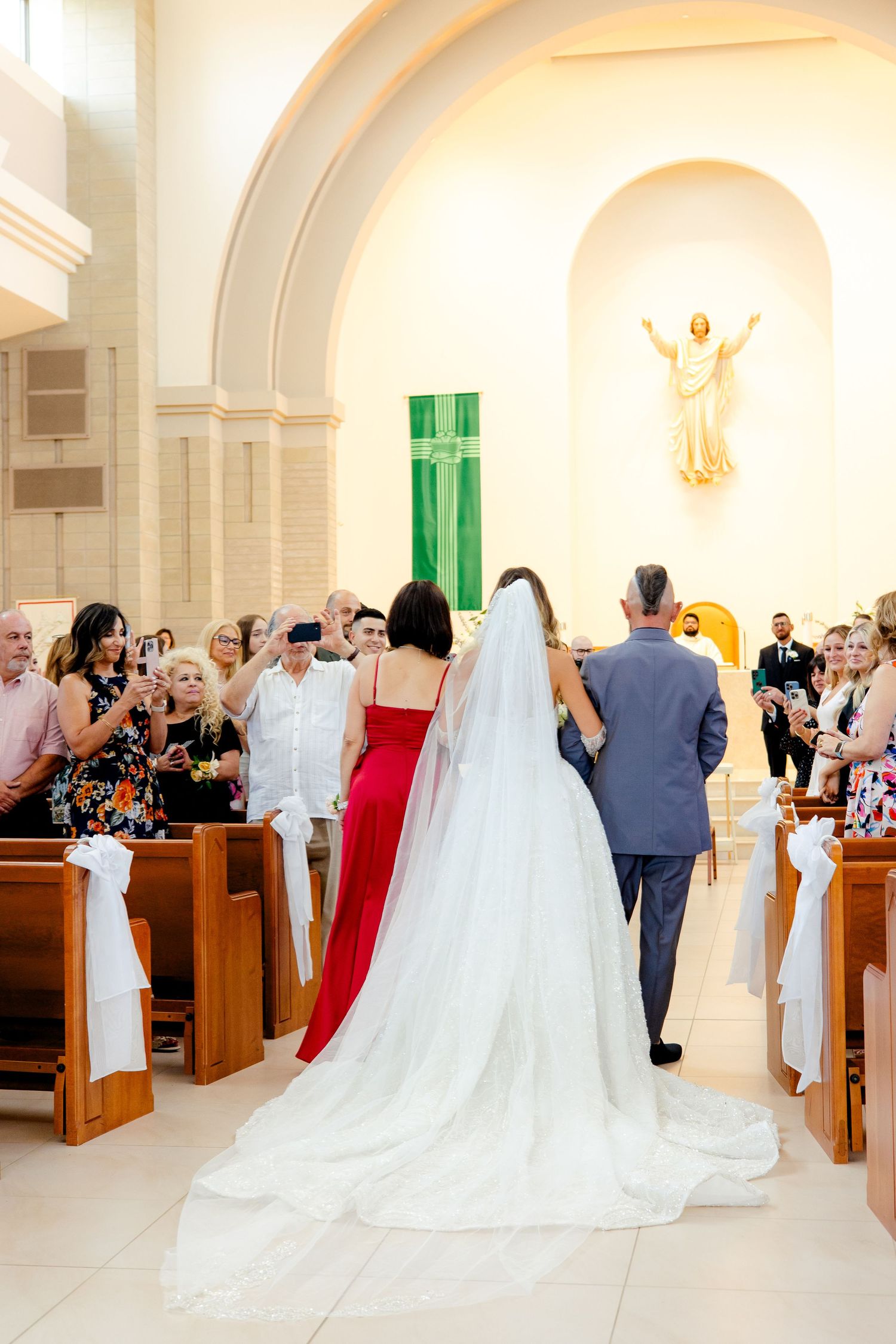 A wedding ceremony in progress at a modern church with arched ceilings and religious artwork.