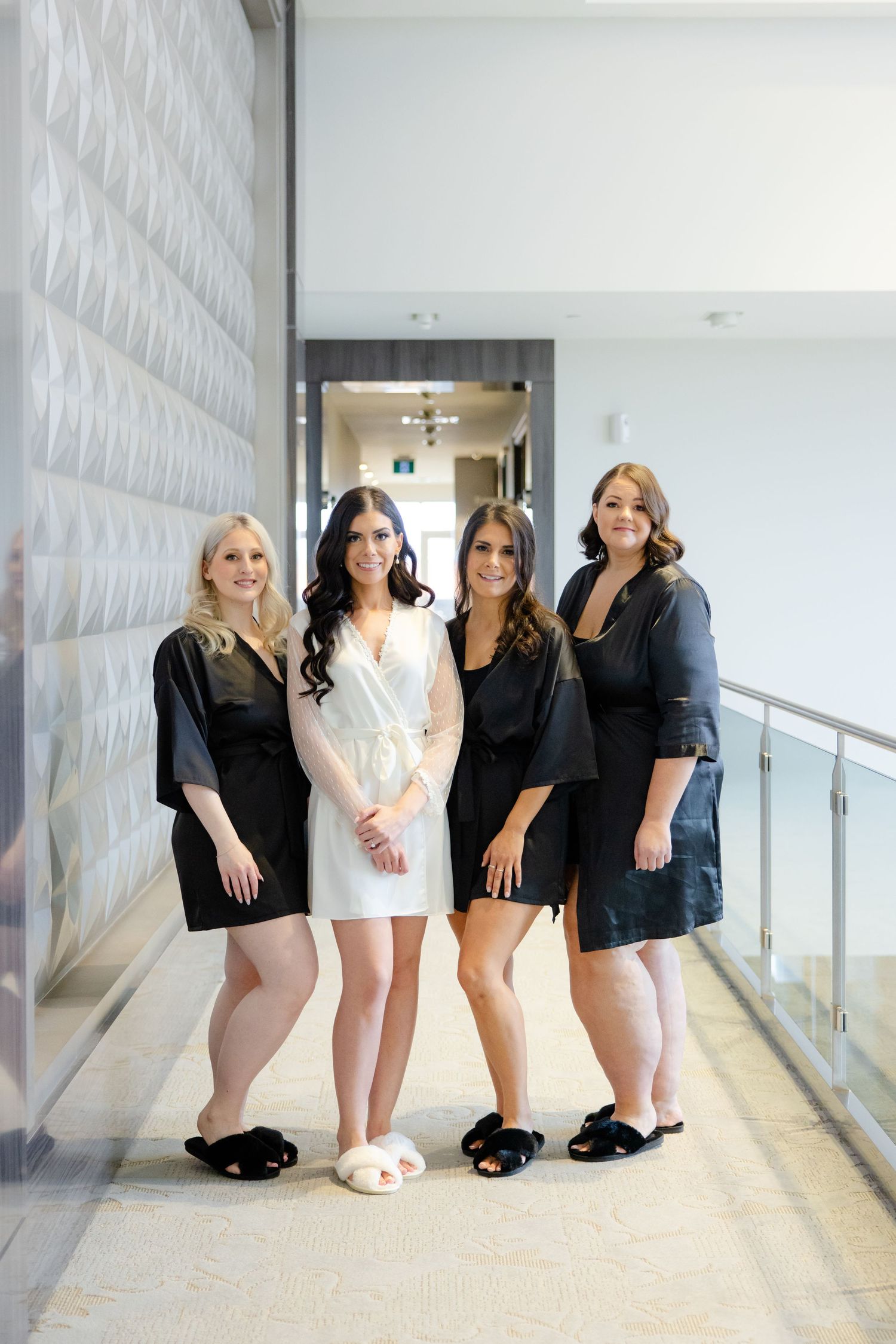 Four women in coordinated black and white outfits standing in hallway.