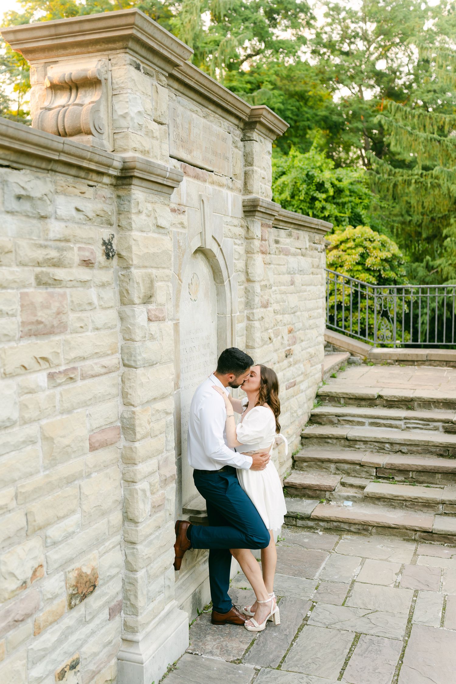 A romantic moment captured against stone architecture with garden steps and greenery.