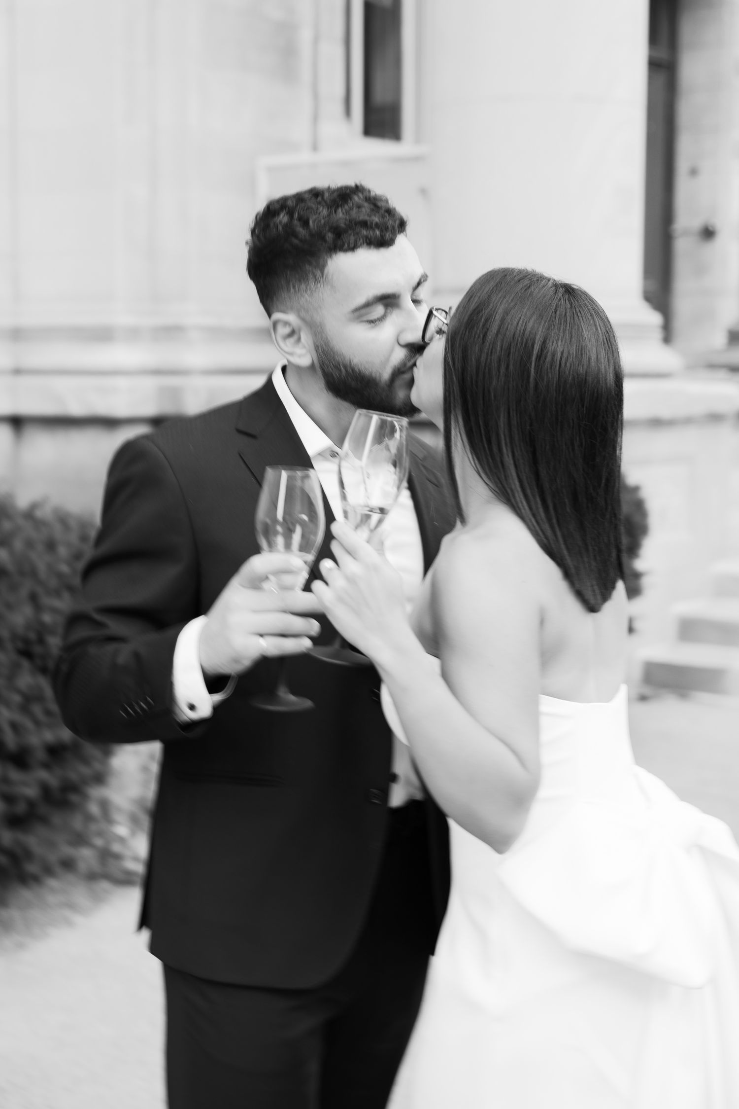 Romantic couple in formal attire sharing champagne and an intimate moment at an elegant venue.