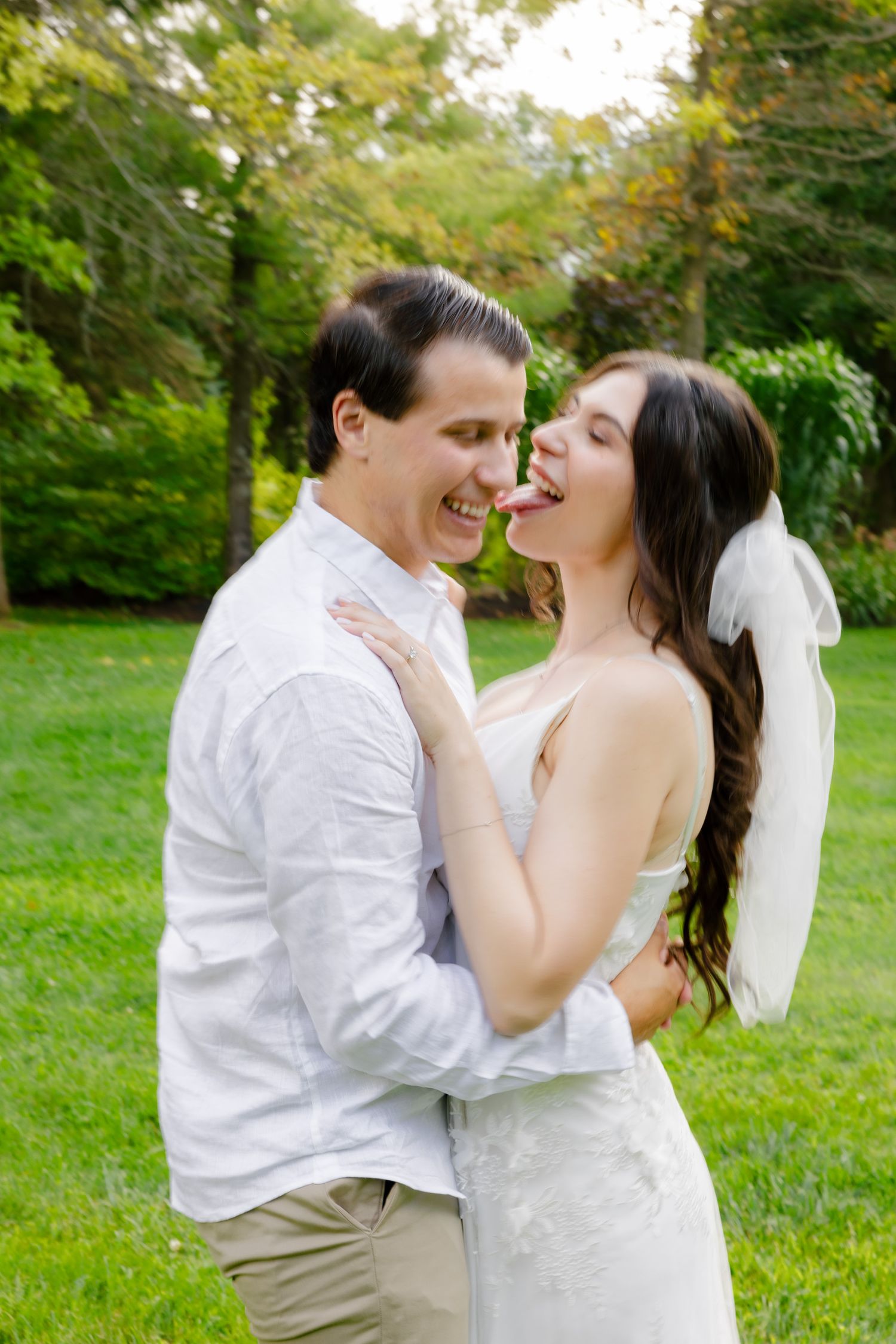 A candid moment of a couple sharing laughter during their wedding photoshoot outdoors.