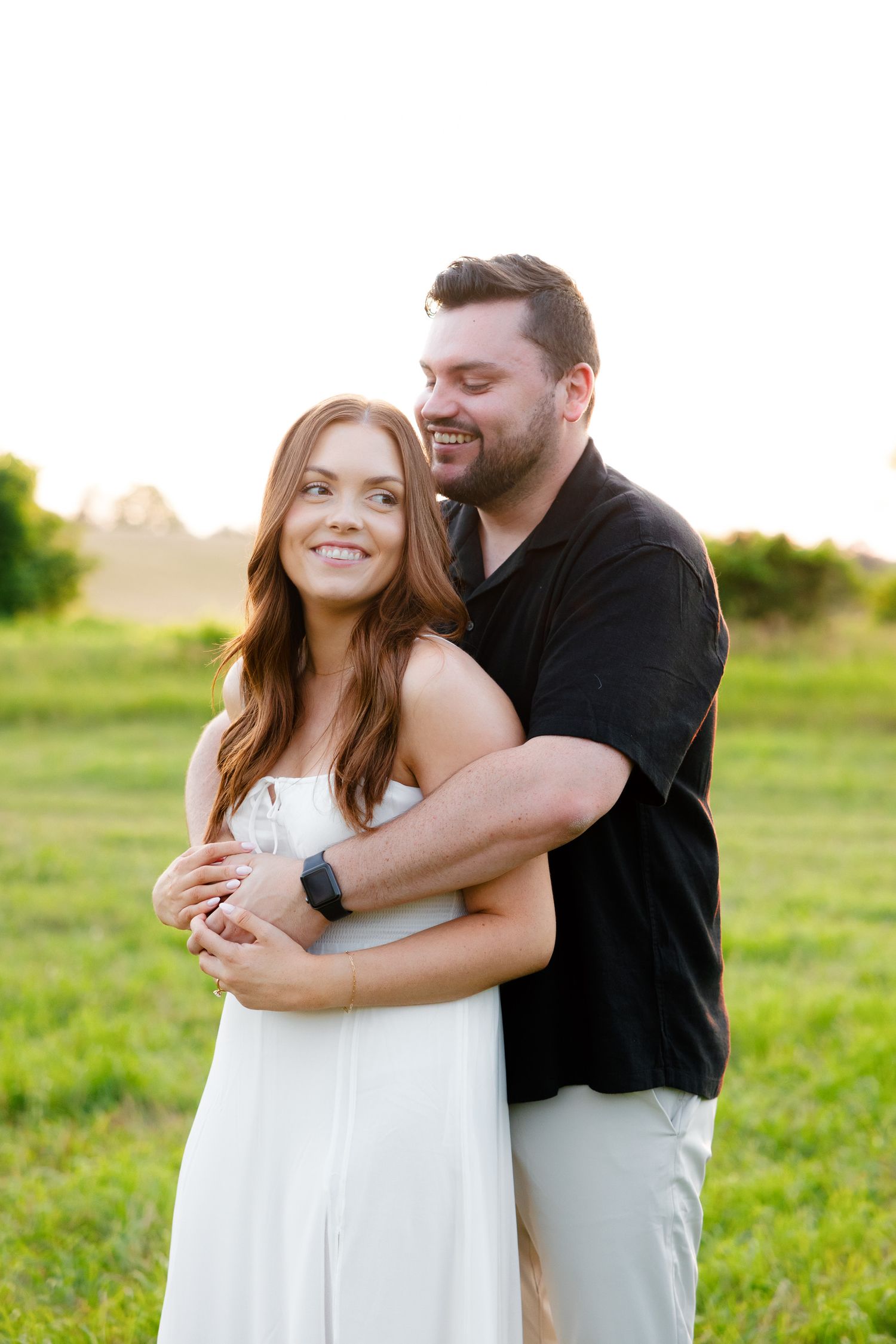 Joyful couple embracing in outdoor setting with natural golden light.
