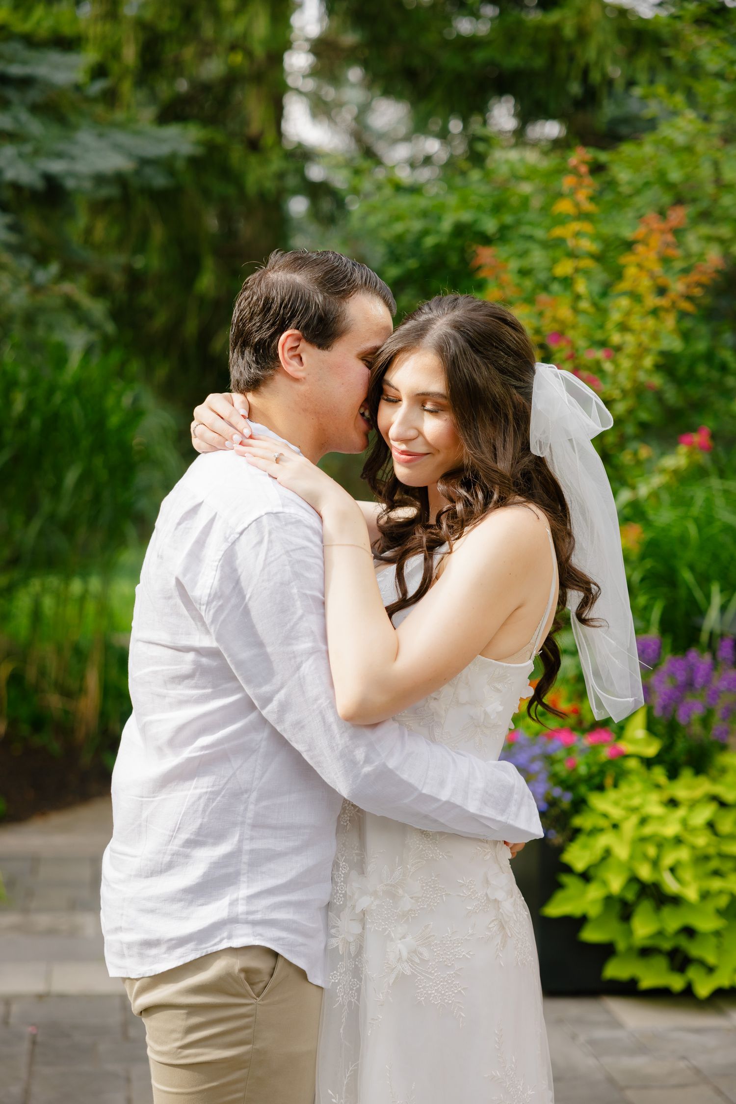 An intimate moment shared between a couple in a garden with vibrant flowers and greenery.