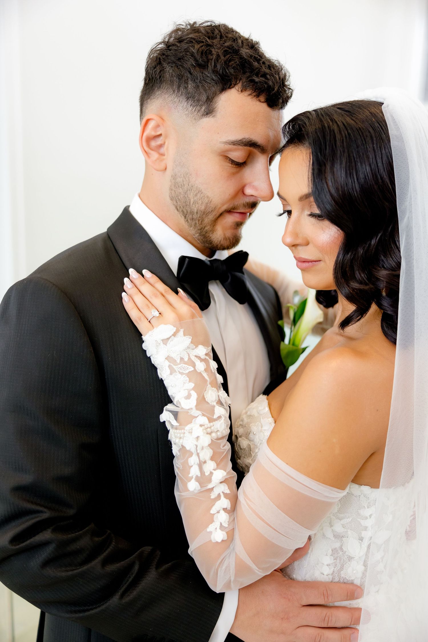 An intimate portrait of newlyweds sharing a close embrace in their wedding attire.