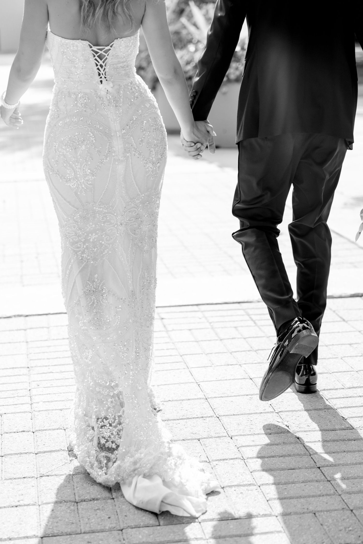 Close-up details of a lace wedding dress and formal suit as couple walks together.