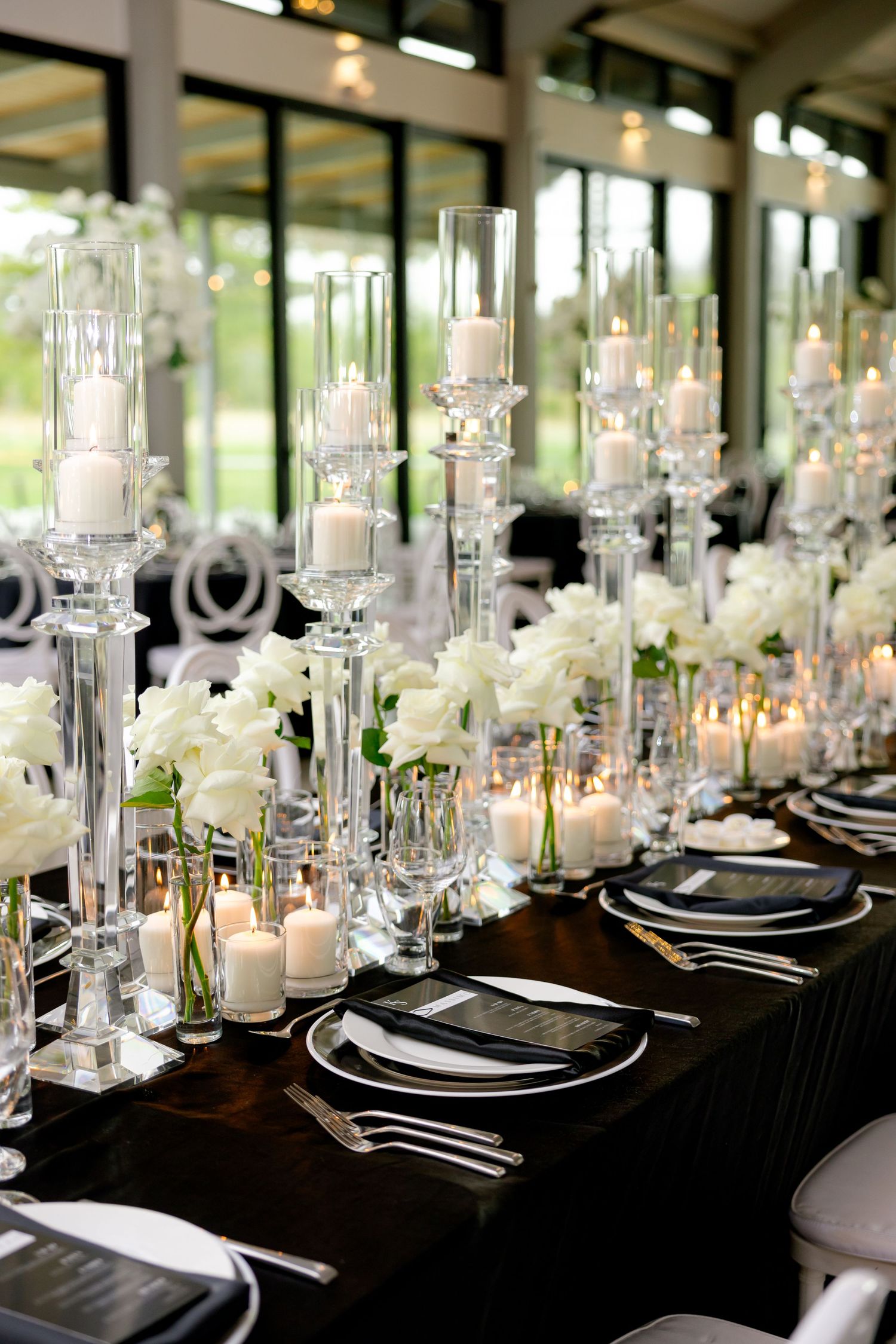 Modern wedding reception table with glass candelabras and white floral arrangements.