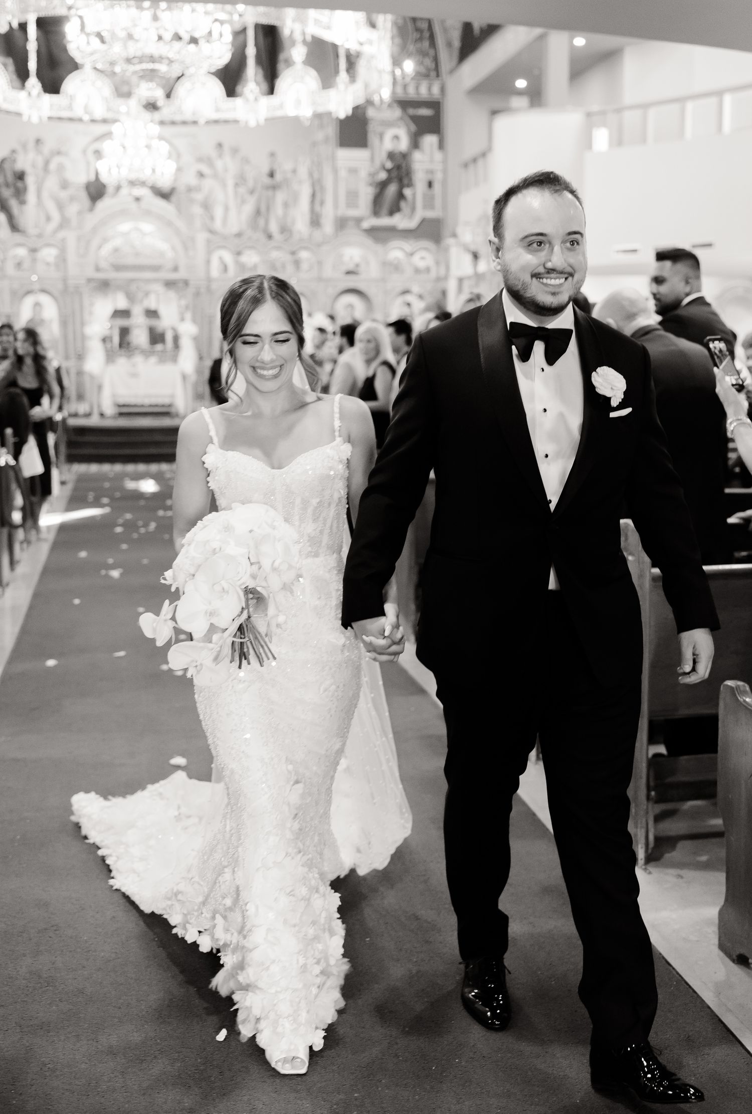 A black and white wedding photo showing a couple walking down the church aisle after their ceremony.