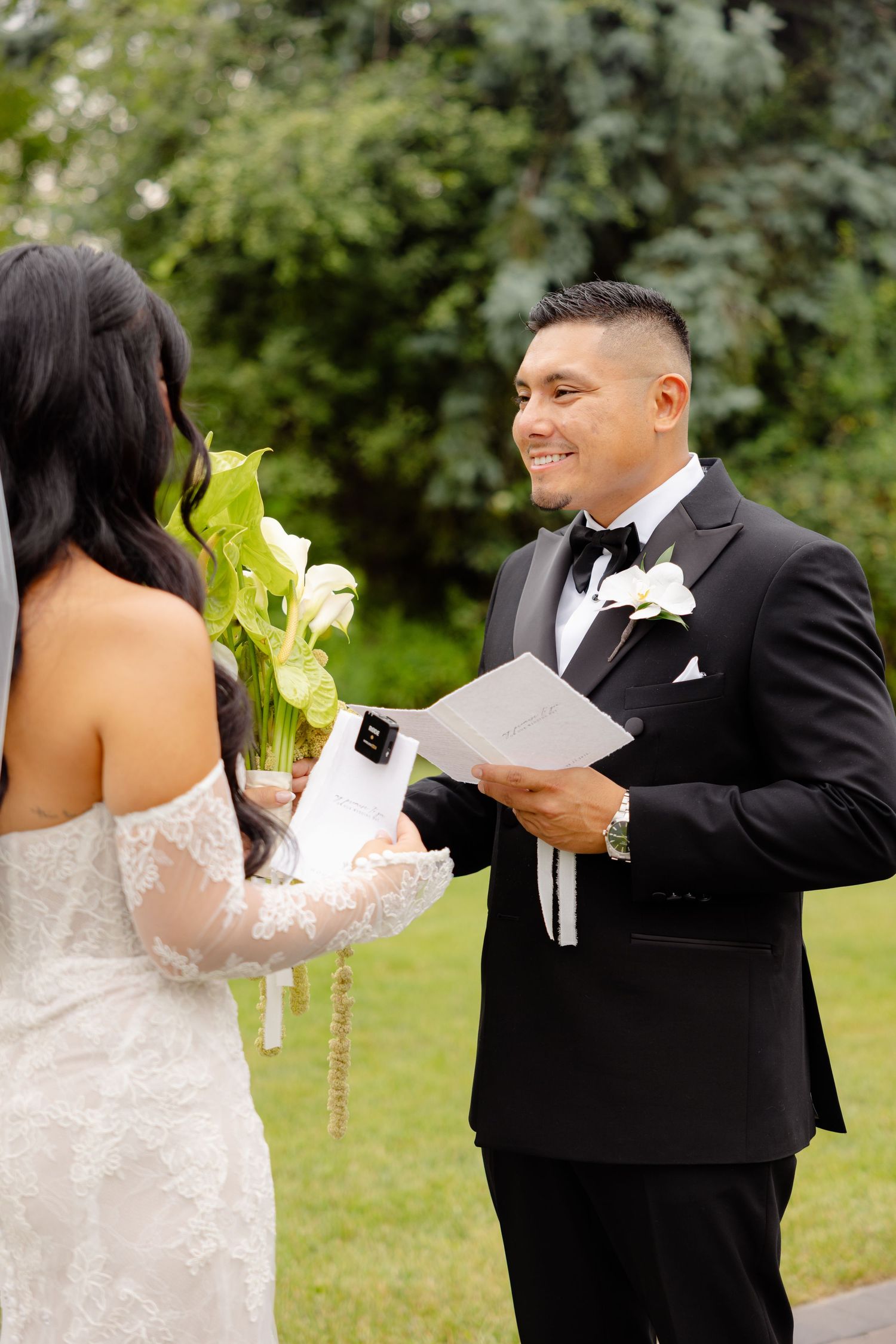 Couple in formal wedding attire shares a joyful first dance moment in a lush garden setting.