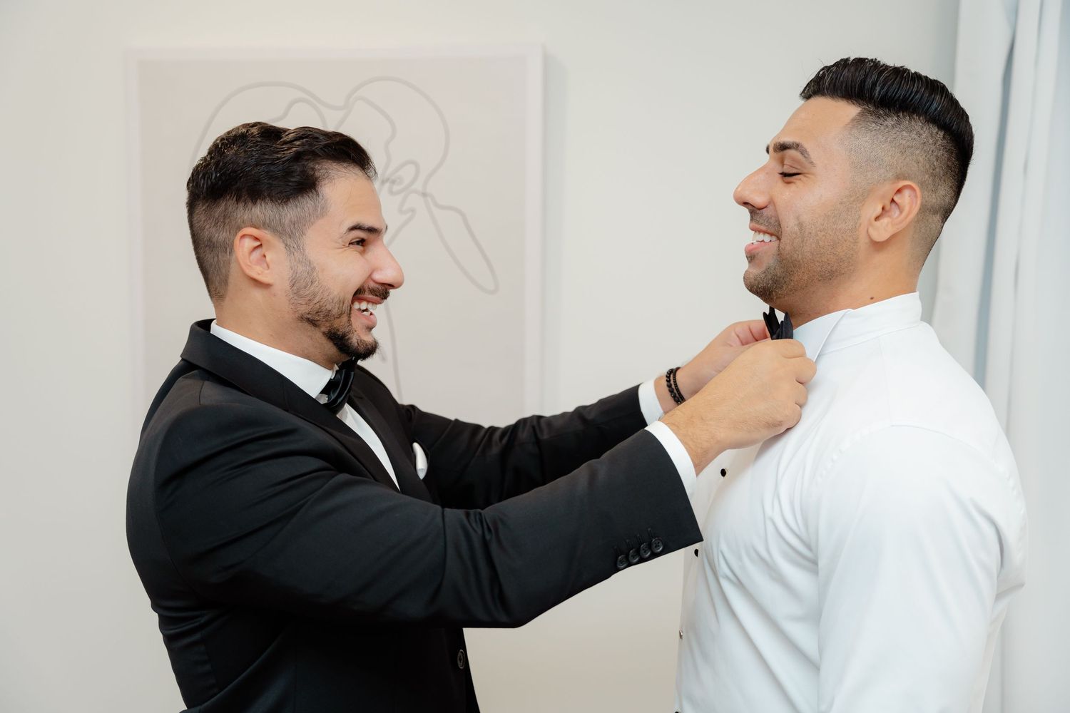 Groomsmen sharing a candid moment while adjusting formal attire before ceremony.
