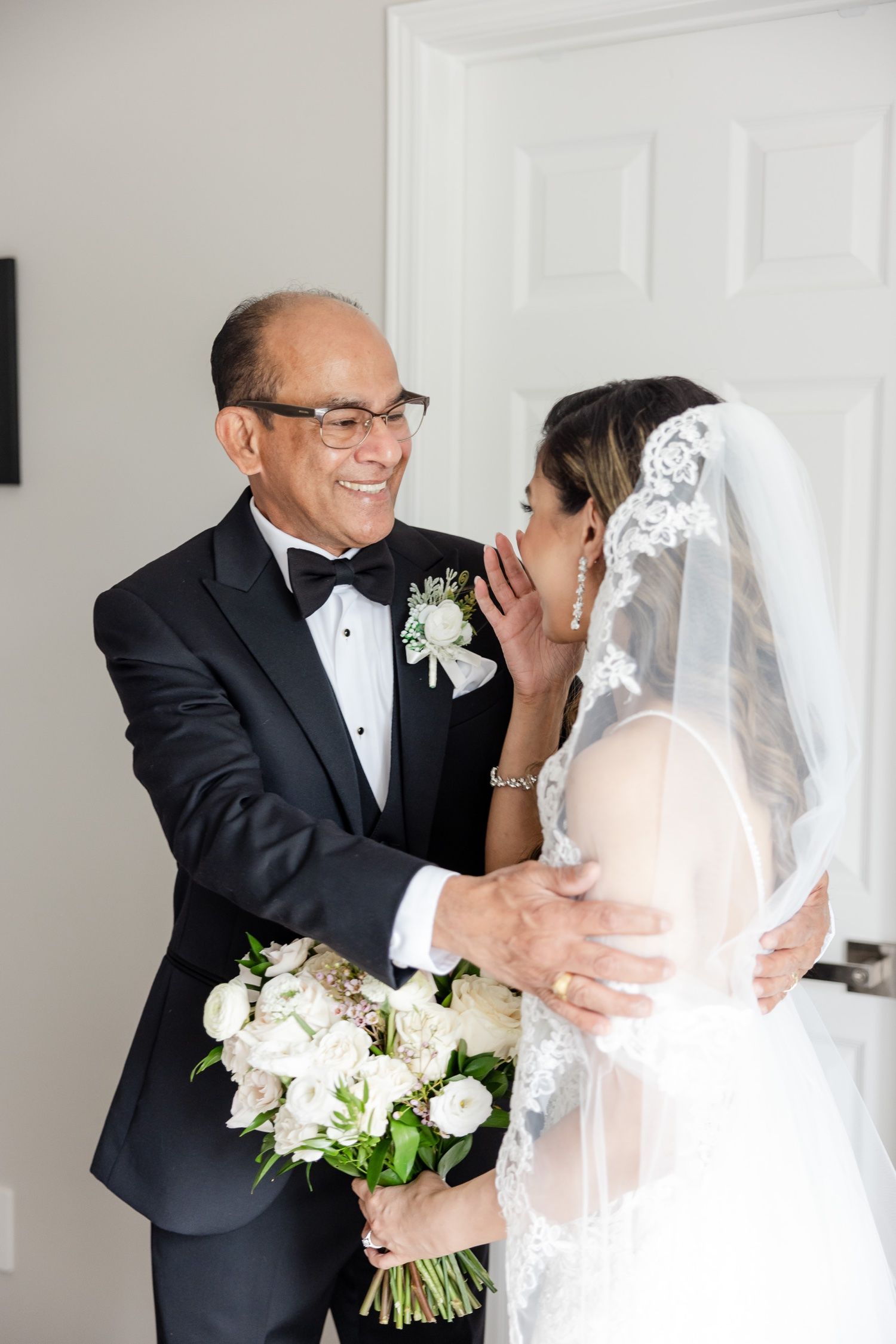 Touching moment during wedding preparations with white floral bouquet.