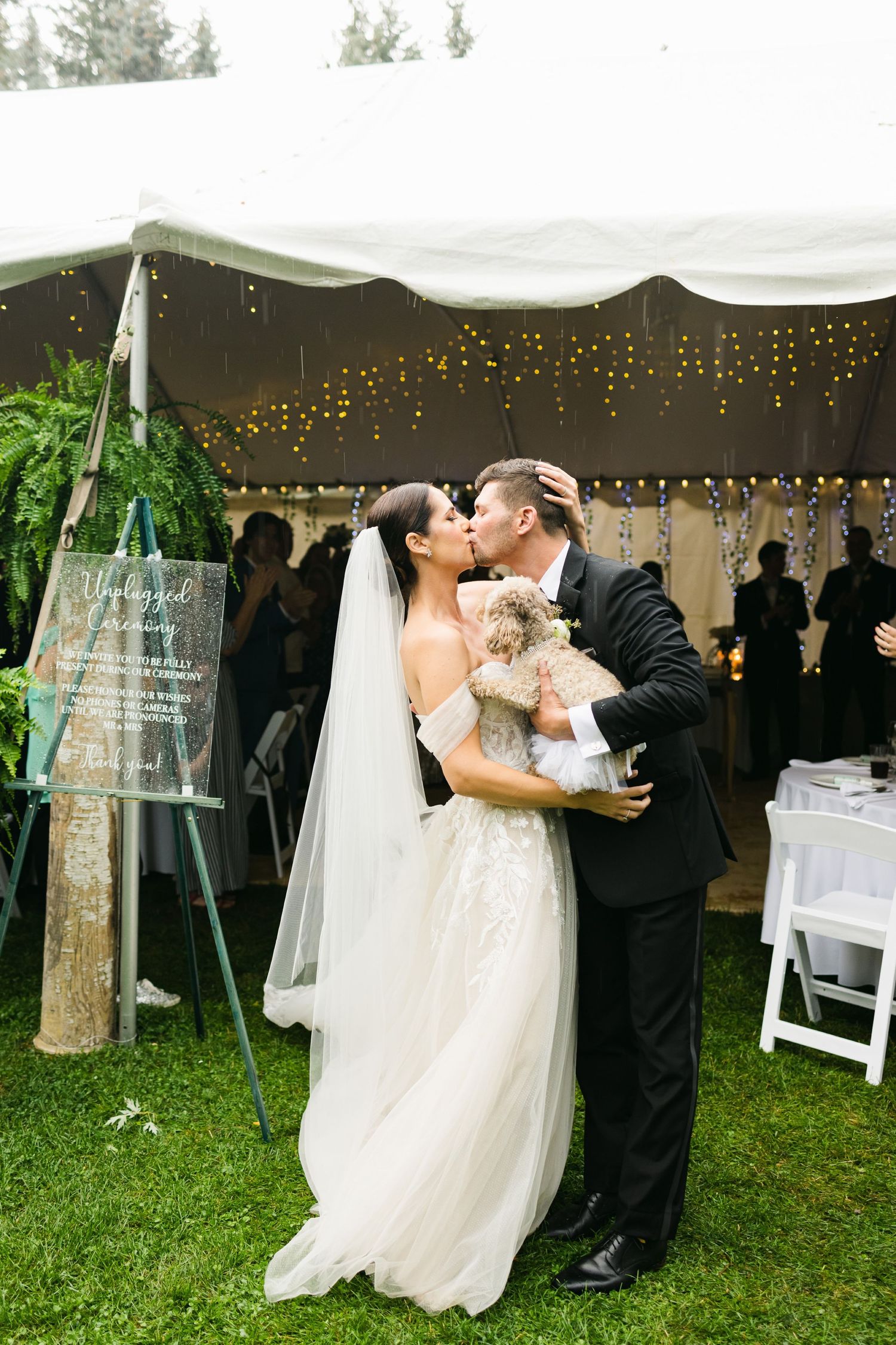 Romantic moment under tent with twinkle lights while holding small dog.