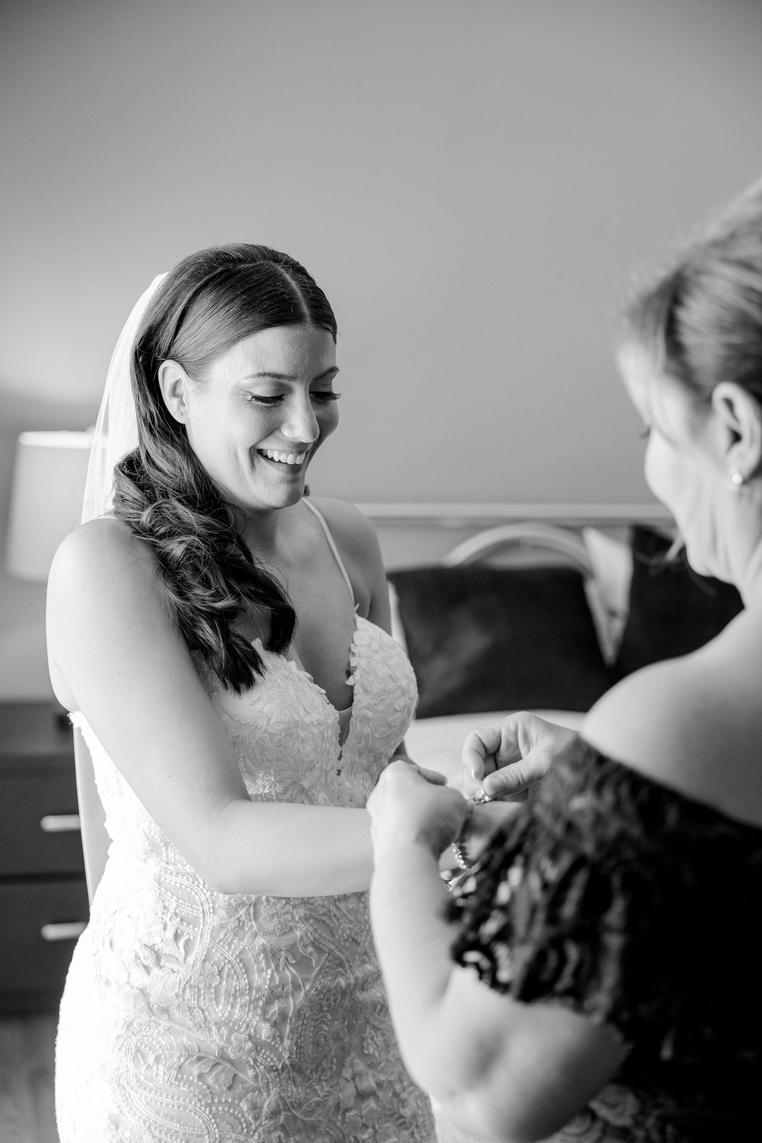 Black and white moment of bride getting ready in a fitted lace wedding gown.