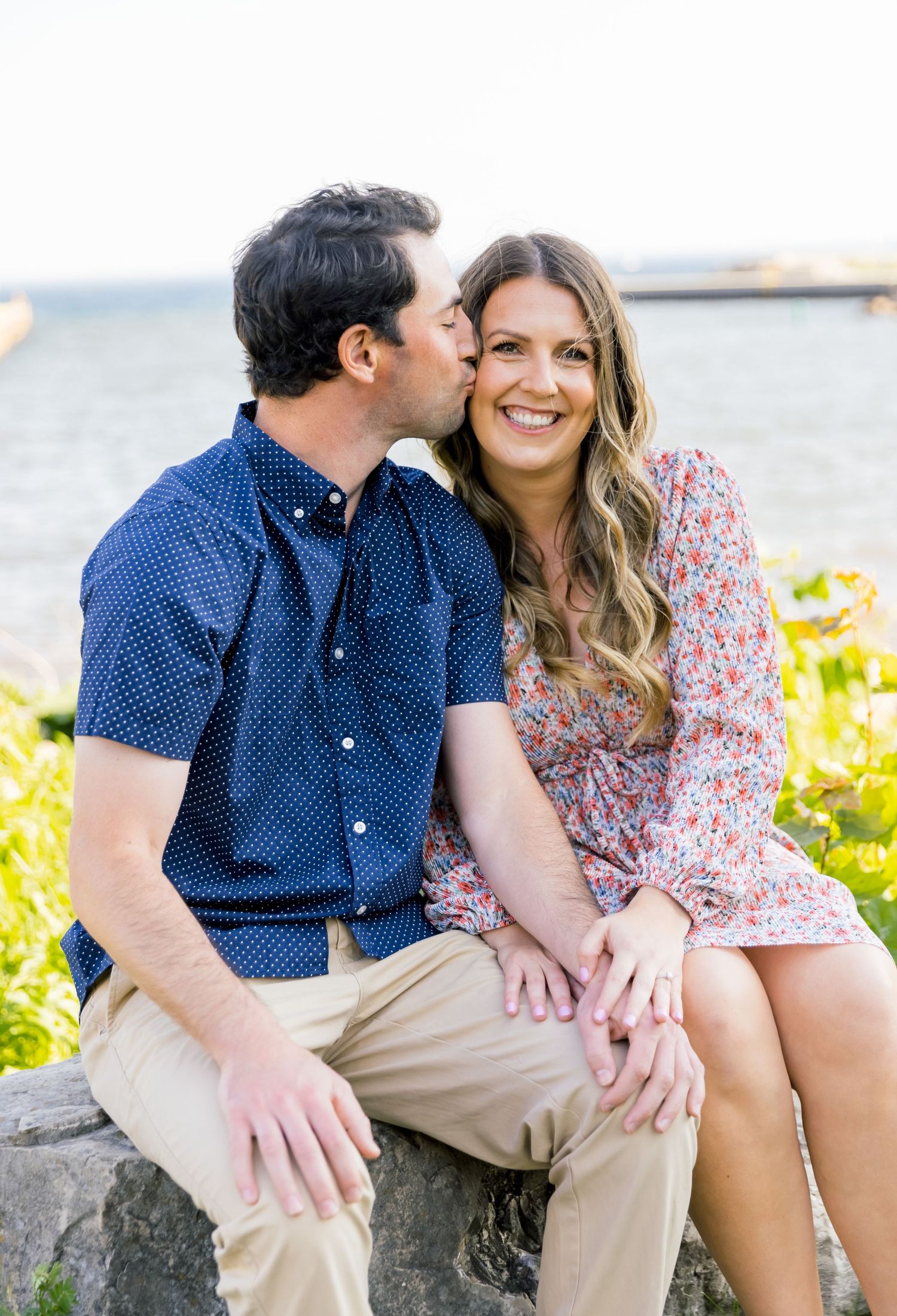 A sweet romantic moment shared between a couple on rocky coastal terrain.