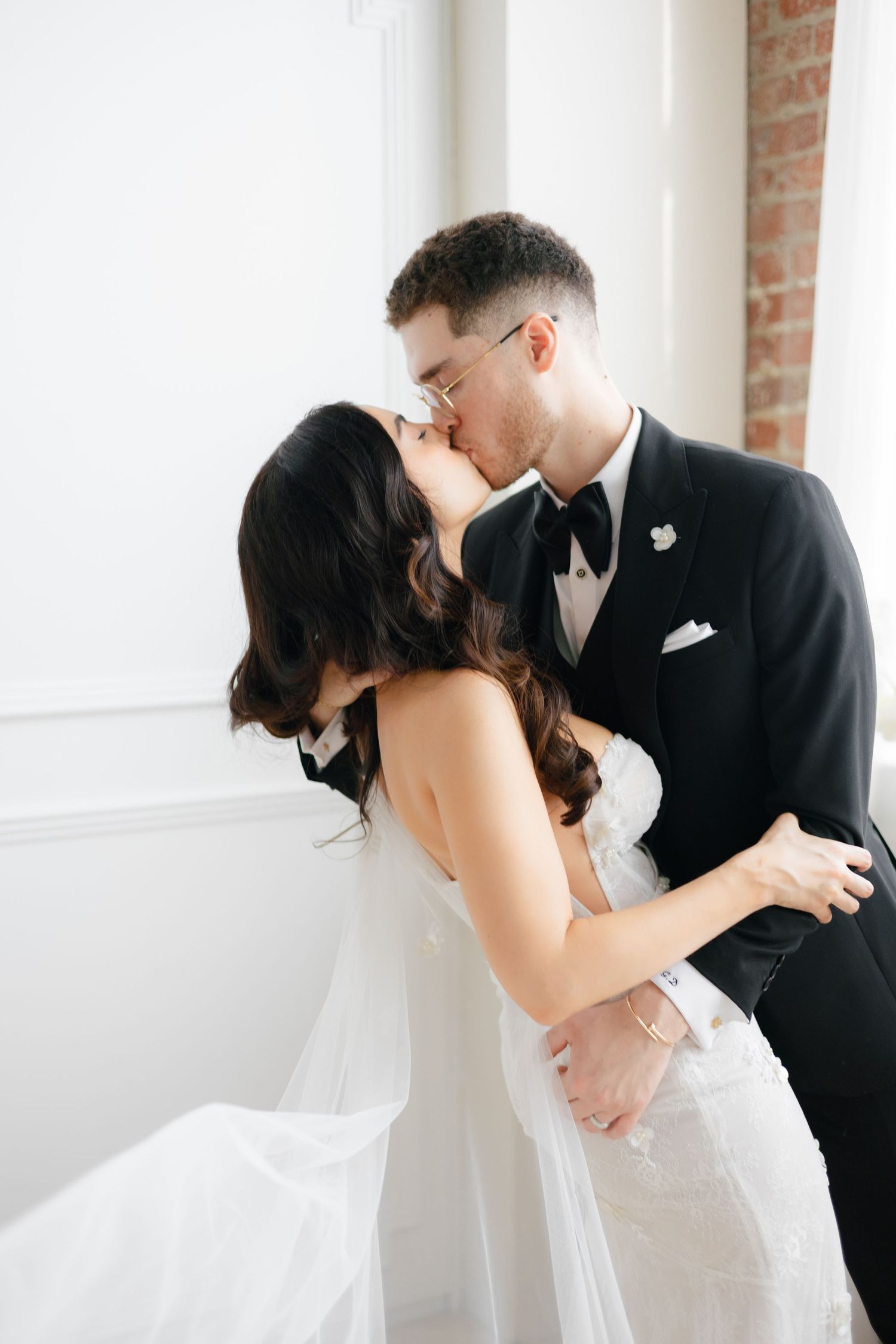 Intimate black and white wedding portrait against brick wall backdrop.