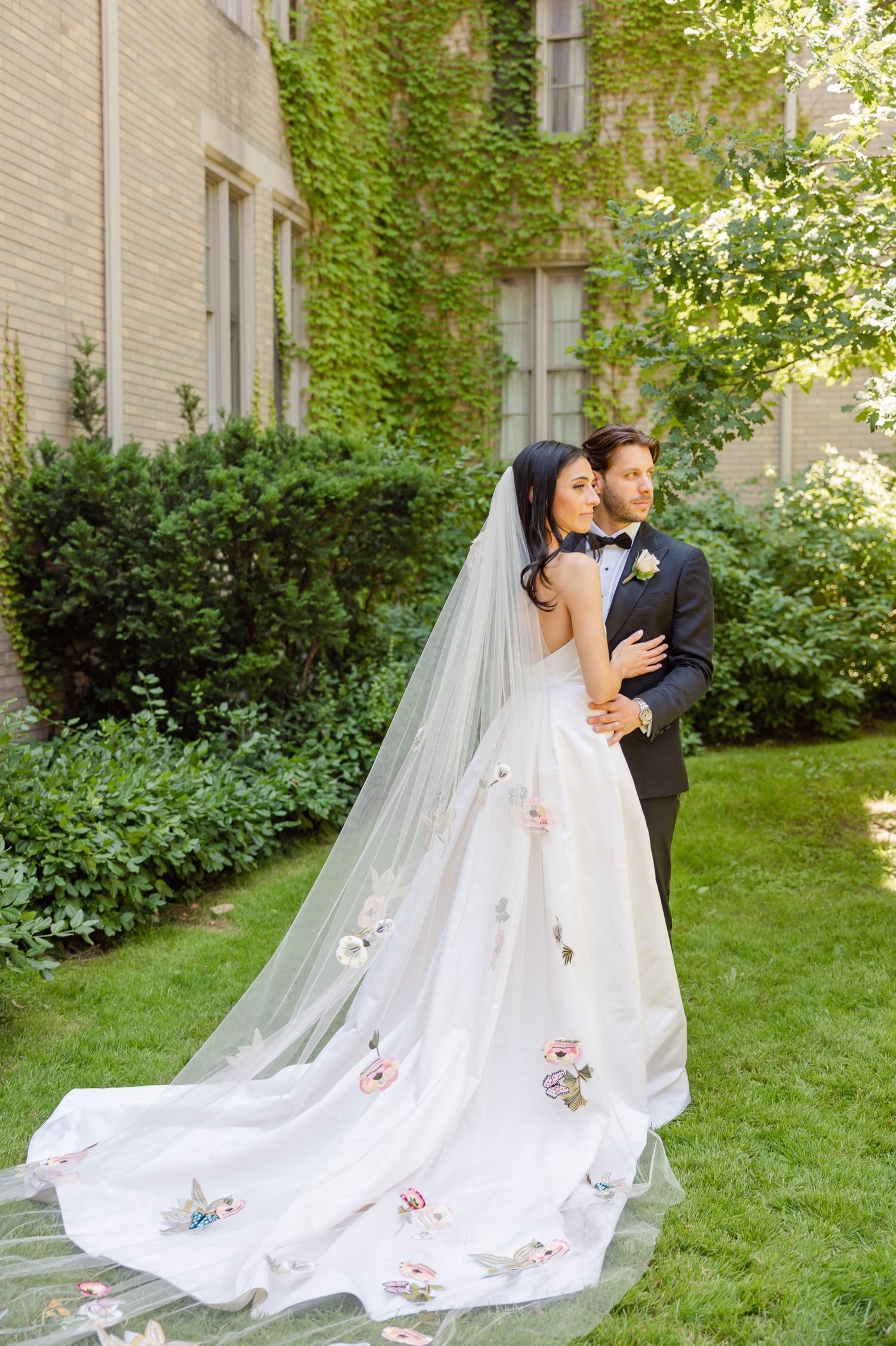 Elegant wedding photo showing a couple's side profile with a flowing floral-detailed train.