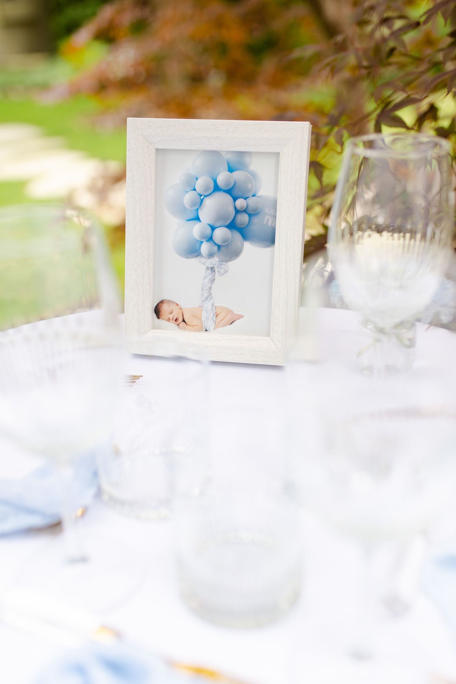 A framed illustration of blue balloons displayed on a white tablecloth.
