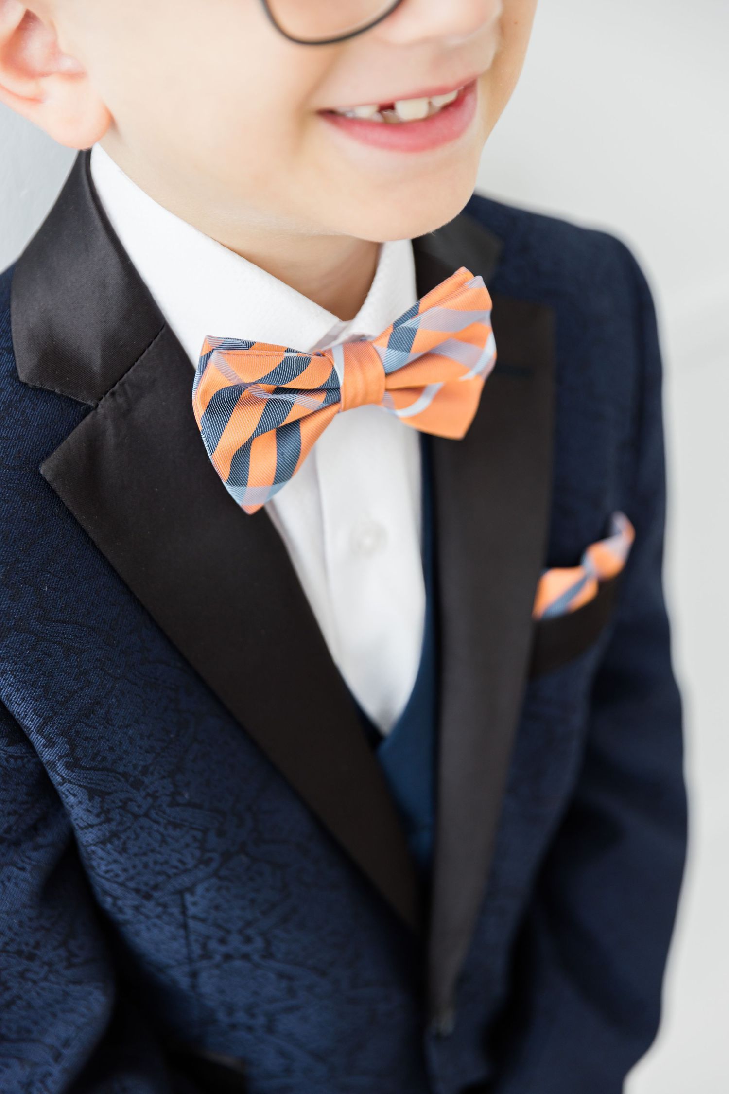 Detail shot of orange striped bowtie and navy suit lapel.