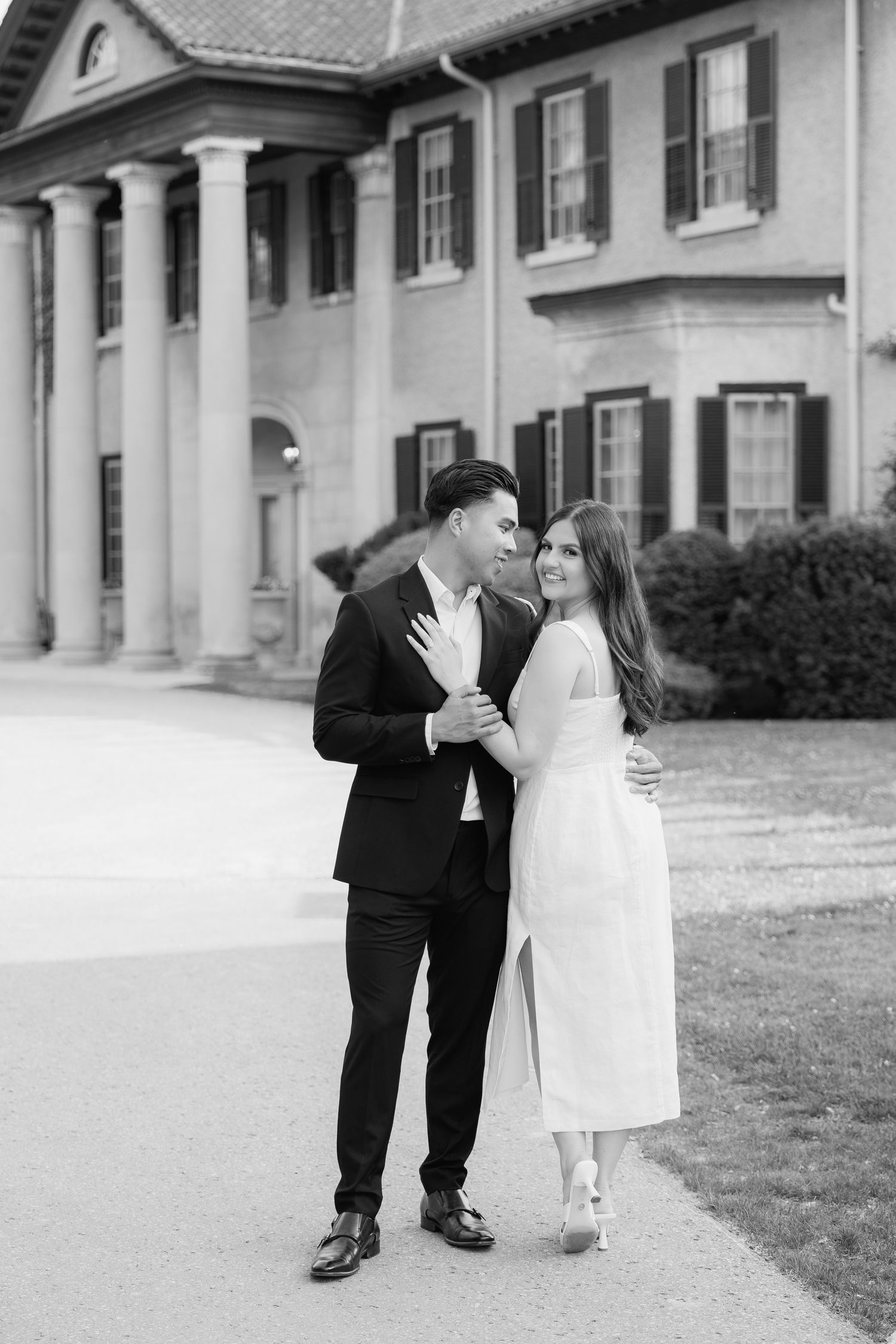Black and white portrait of couple sharing intimate moment outside grand historic building.