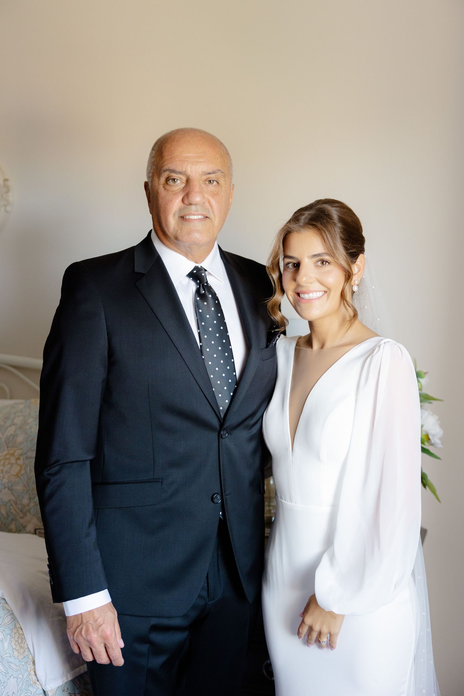 Formal portrait featuring classic black suit and elegant white wedding dress in soft lighting.