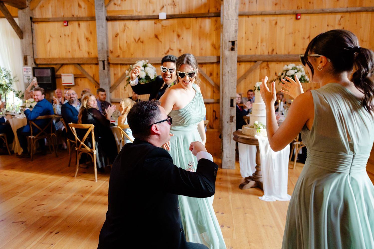 Wedding guests raise their glasses in celebration during a barn reception.