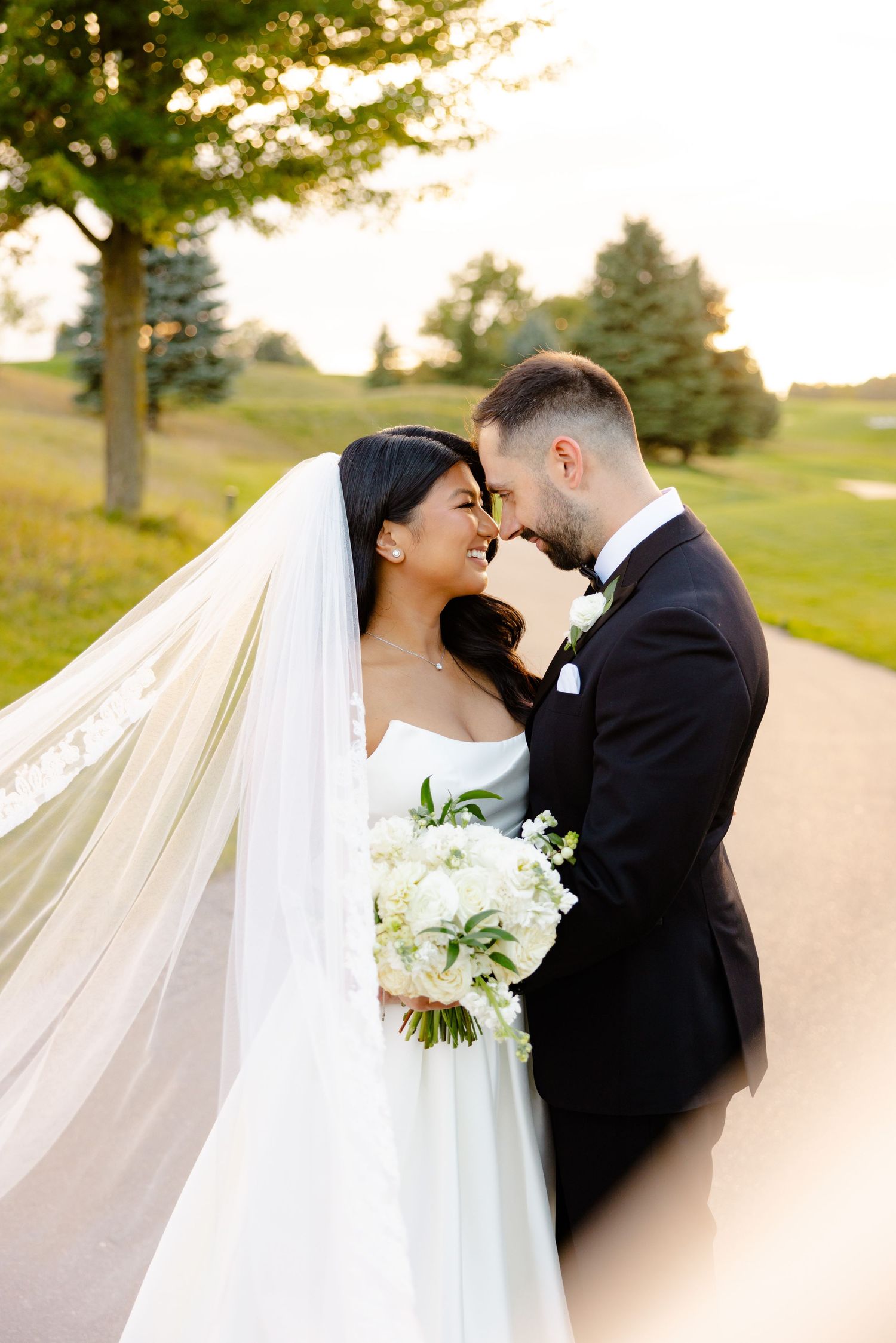 A romantic wedding portrait with the couple embracing on a winding path at sunset.