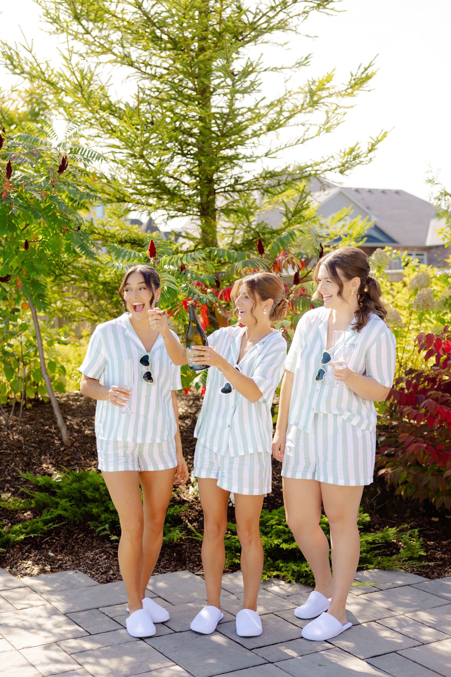 Group in matching striped pajama sets posed in garden with vibrant foliage.