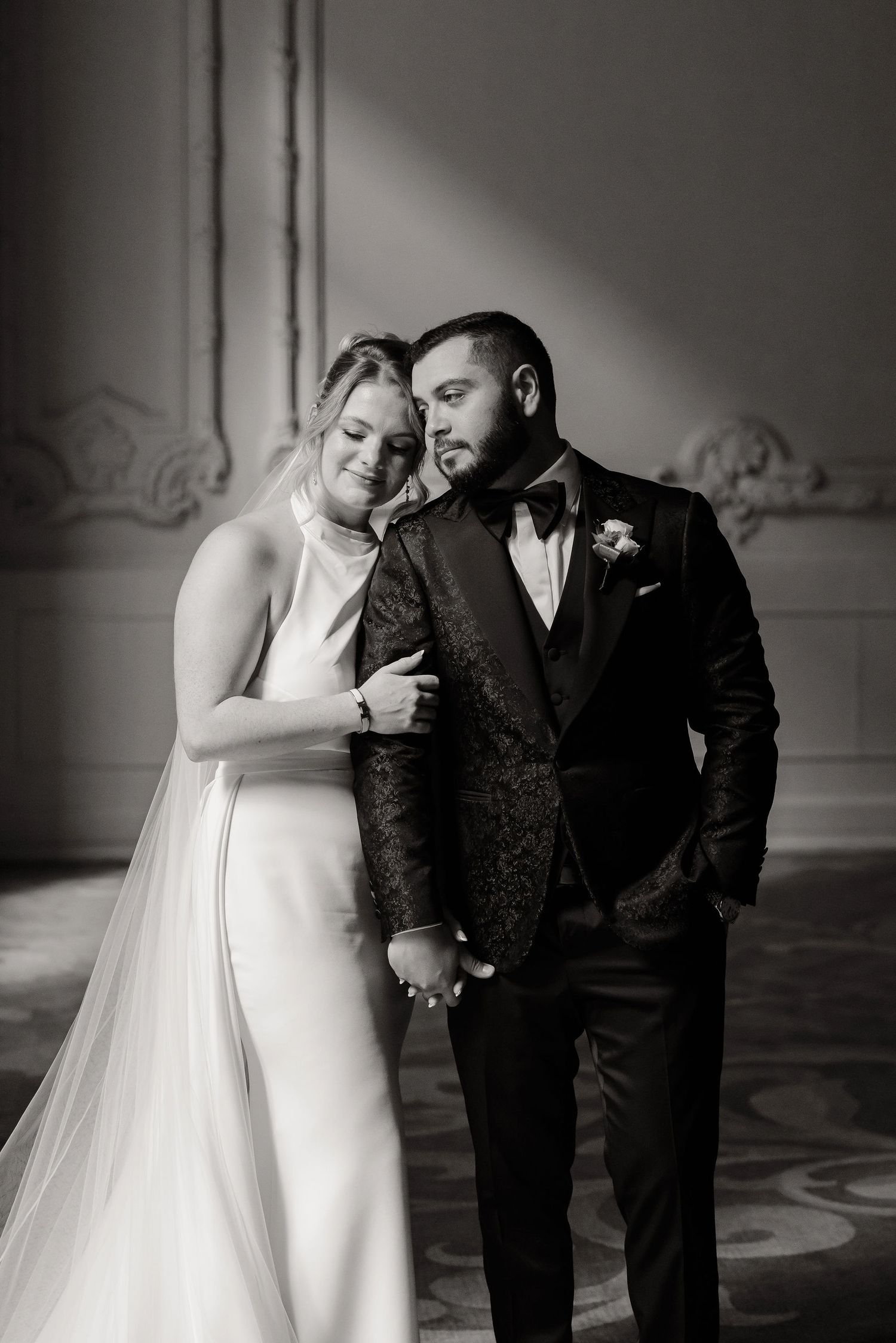 A romantic black and white photo series showing intimate moments between newlyweds in formal wedding attire.