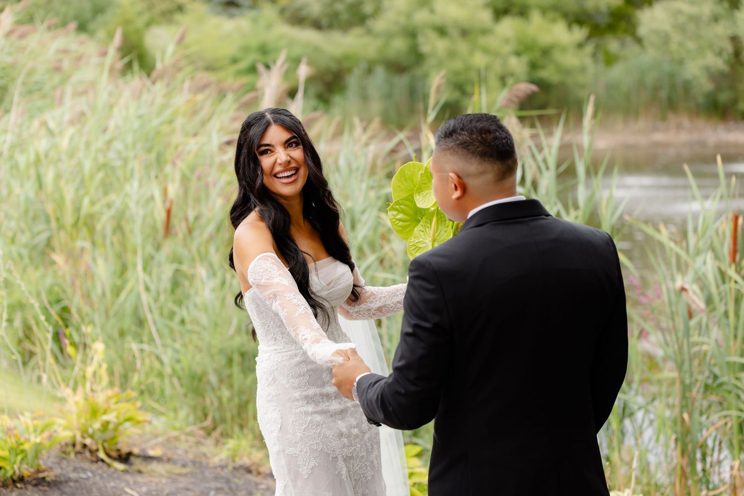 A couple in formal attire stands together at a waterfront location during a romantic photo session.
