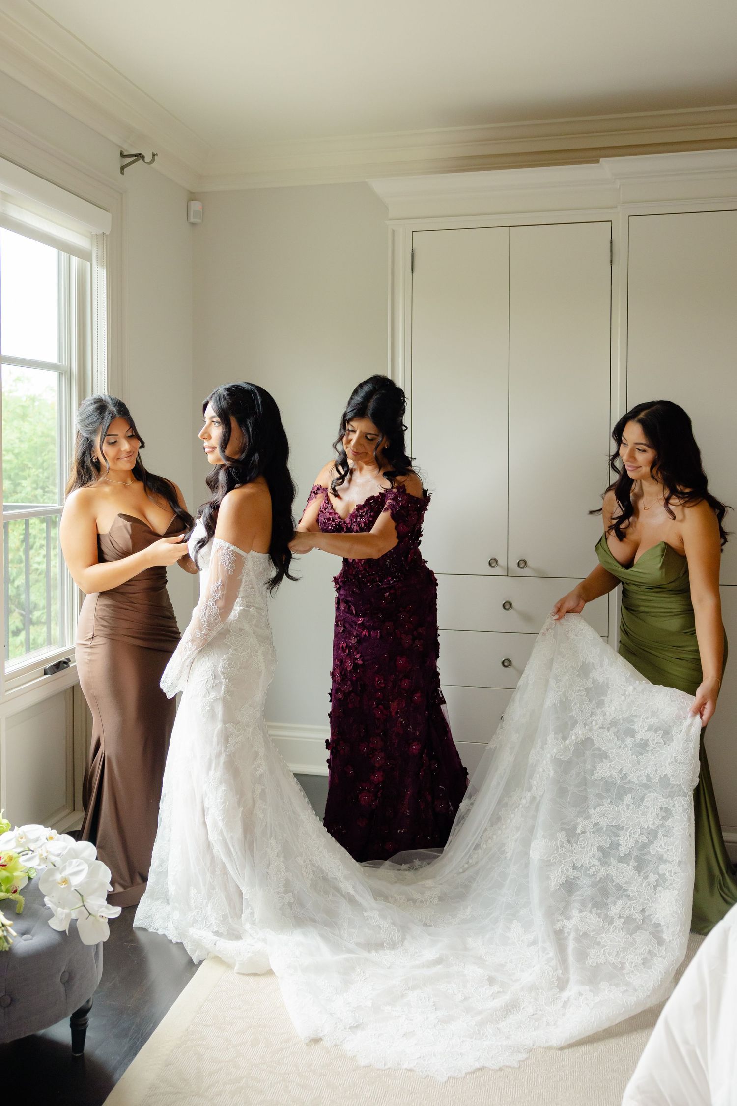 A wedding party helps adjust a bride's long lace train in a white room with windows, shown in multiple angles.
