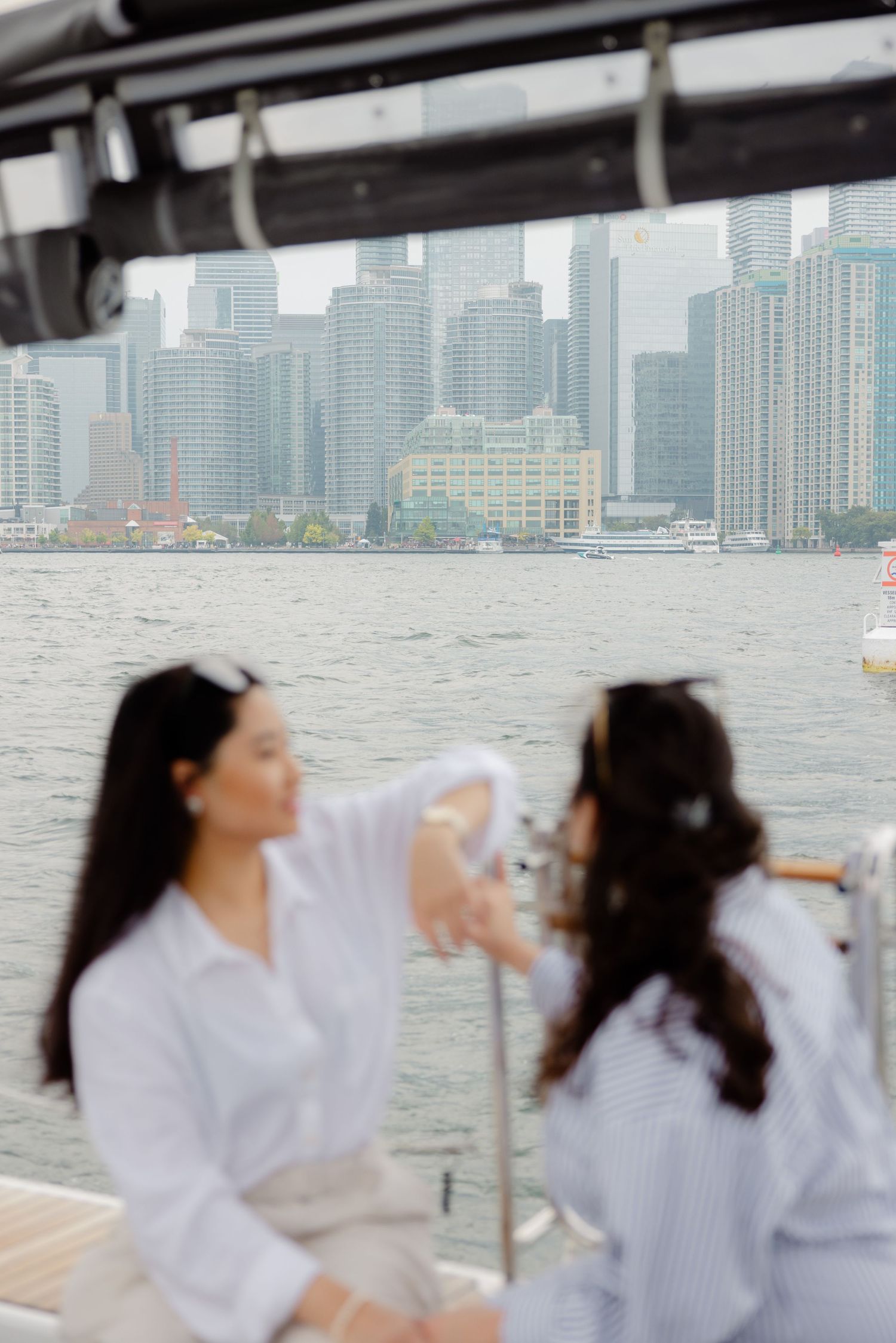 Two people in white shirts enjoying a boat ride with city skyline views across the water.