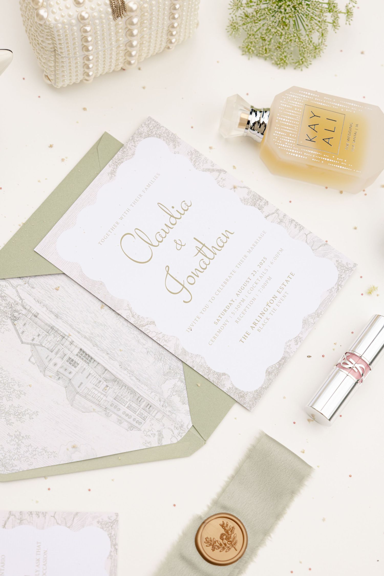 Elegant wedding stationery with wax seals and floral elements arranged on a light marble background.