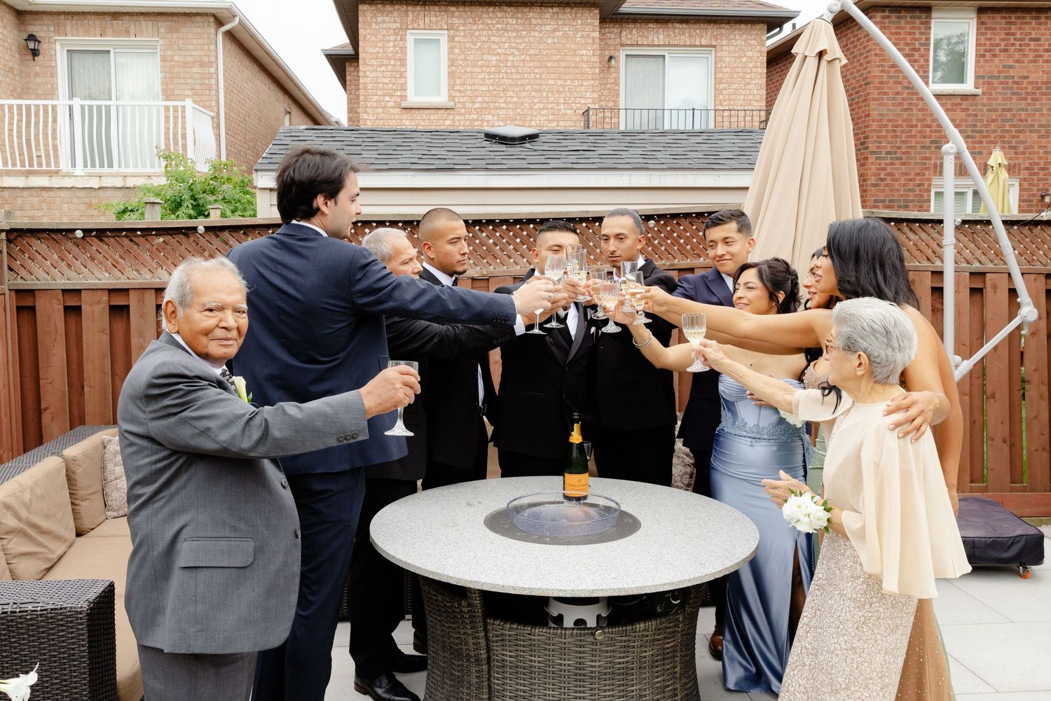 Group of guests gathered around an outdoor patio fire pit during a social gathering at dusk.