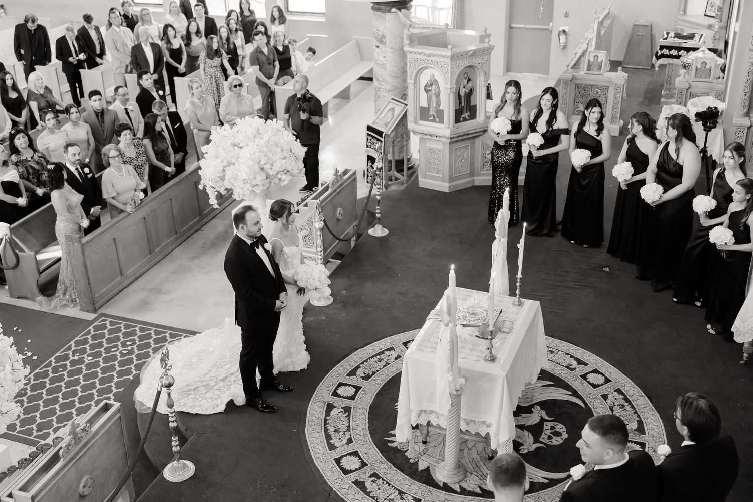 Aerial view of a wedding ceremony in a circular church space with guests surrounding a central altar area.
