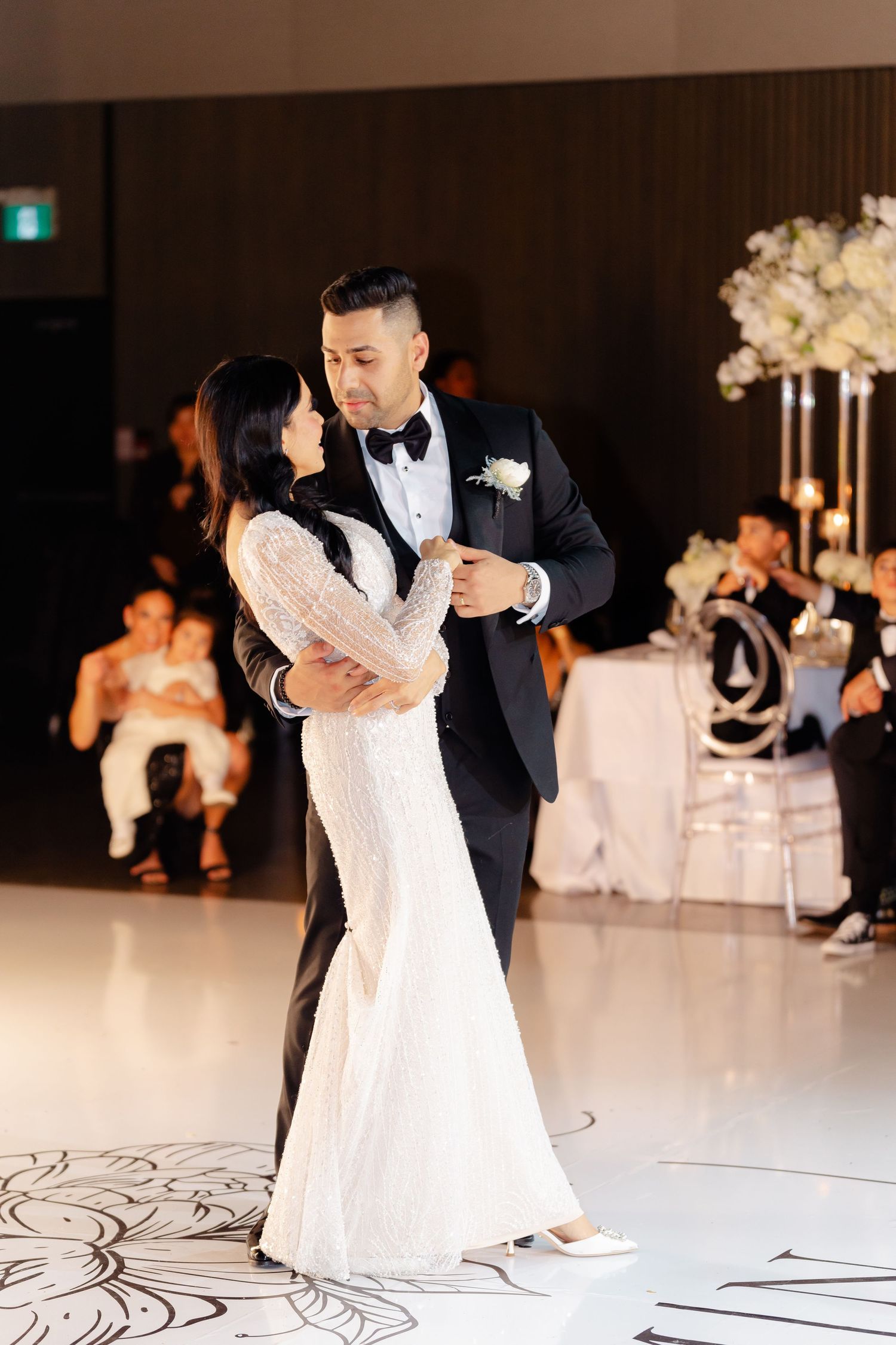 Couple shares first dance on patterned dance floor at wedding reception.